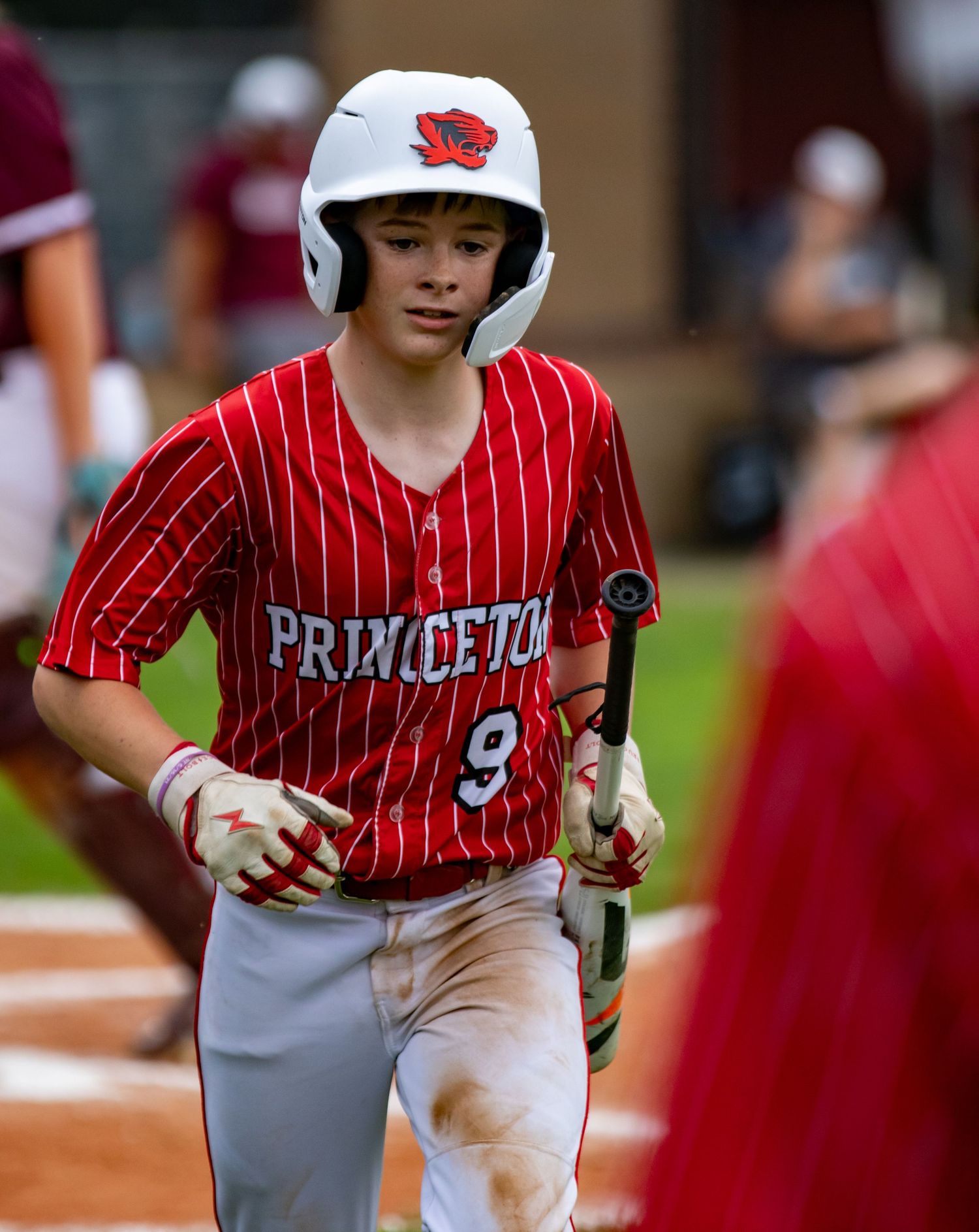 Princeton baseball player number 9 in red pinstripe uniform walking with a bat.