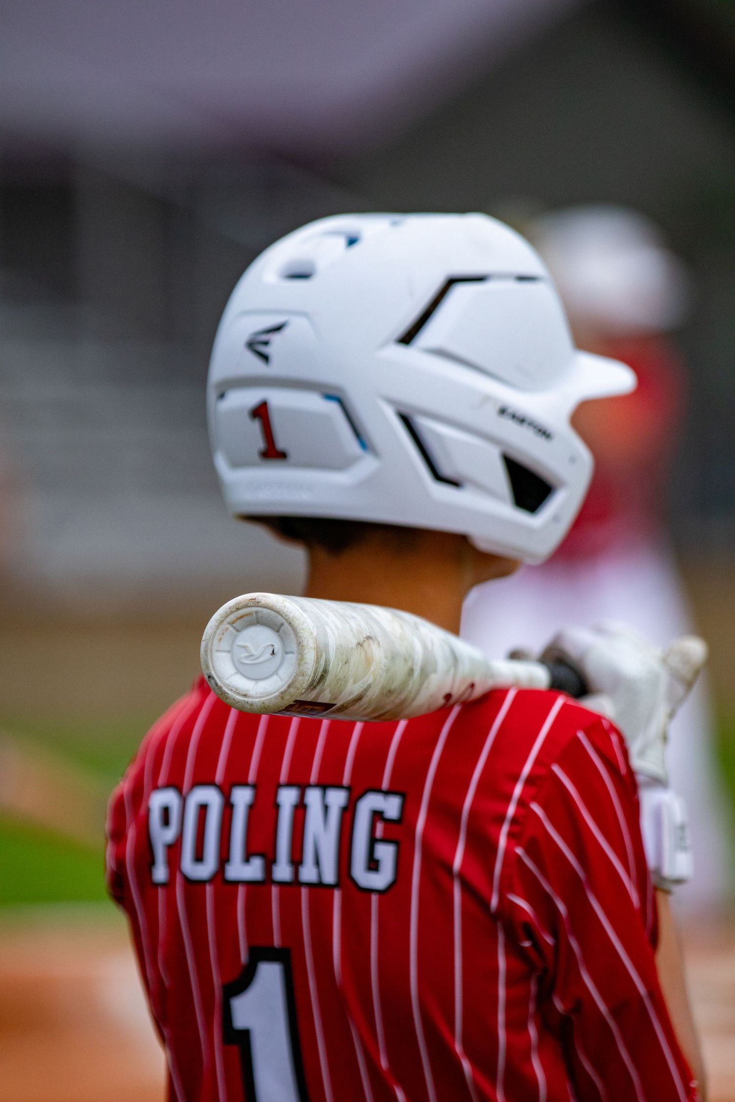 Back view of baseball player #1 Poling in red pinstripe jersey holding Easton bat over shoulder.