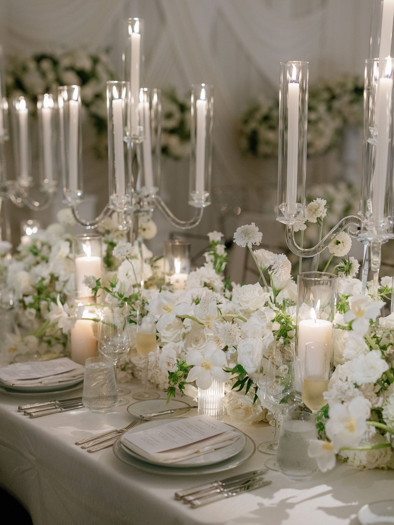 Luxurious white wedding tablescape with crystal candelabras and white floral arrangements.