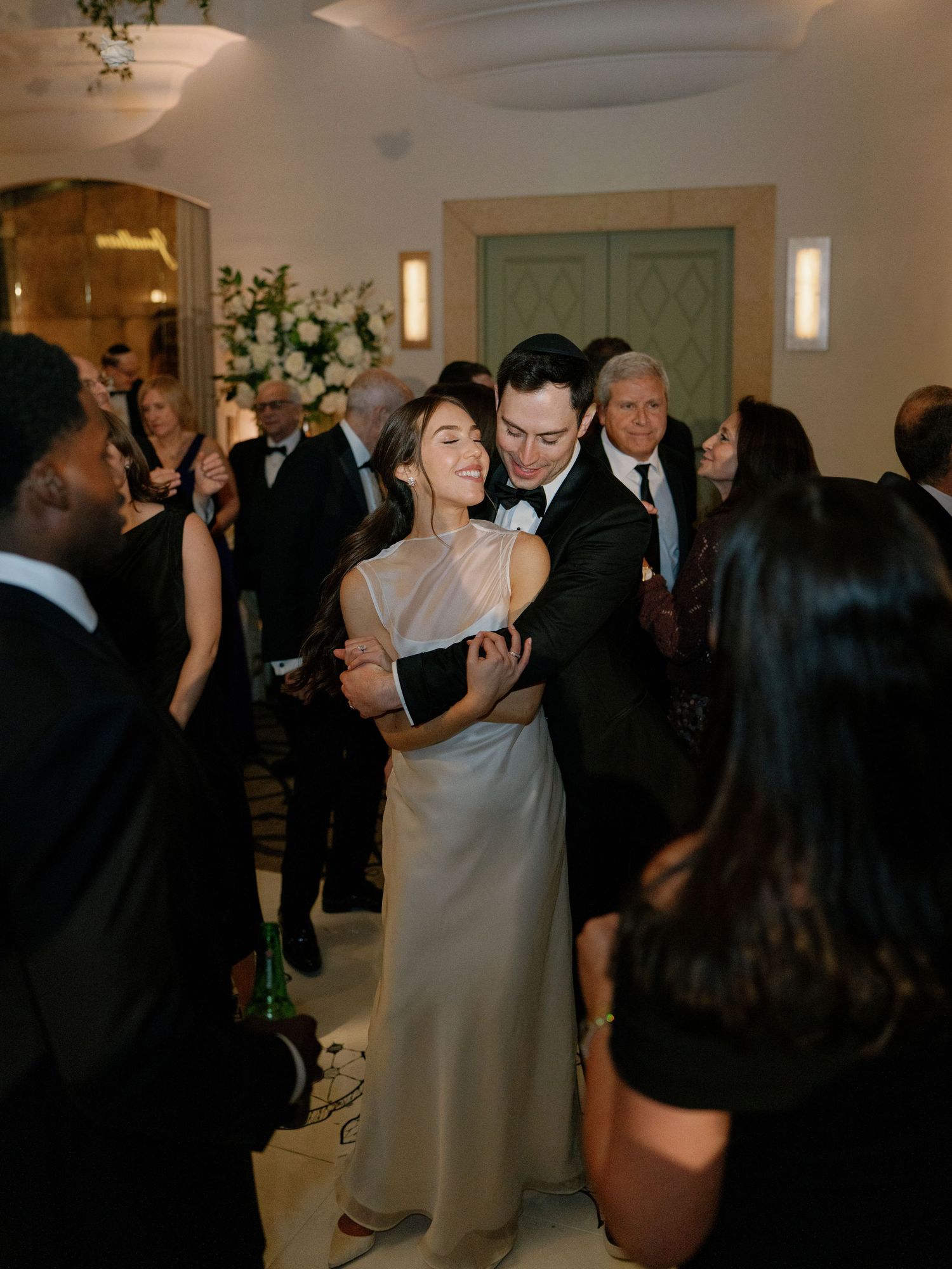 Bride and groom sharing intimate dance moment surrounded by guests at elegant wedding reception.