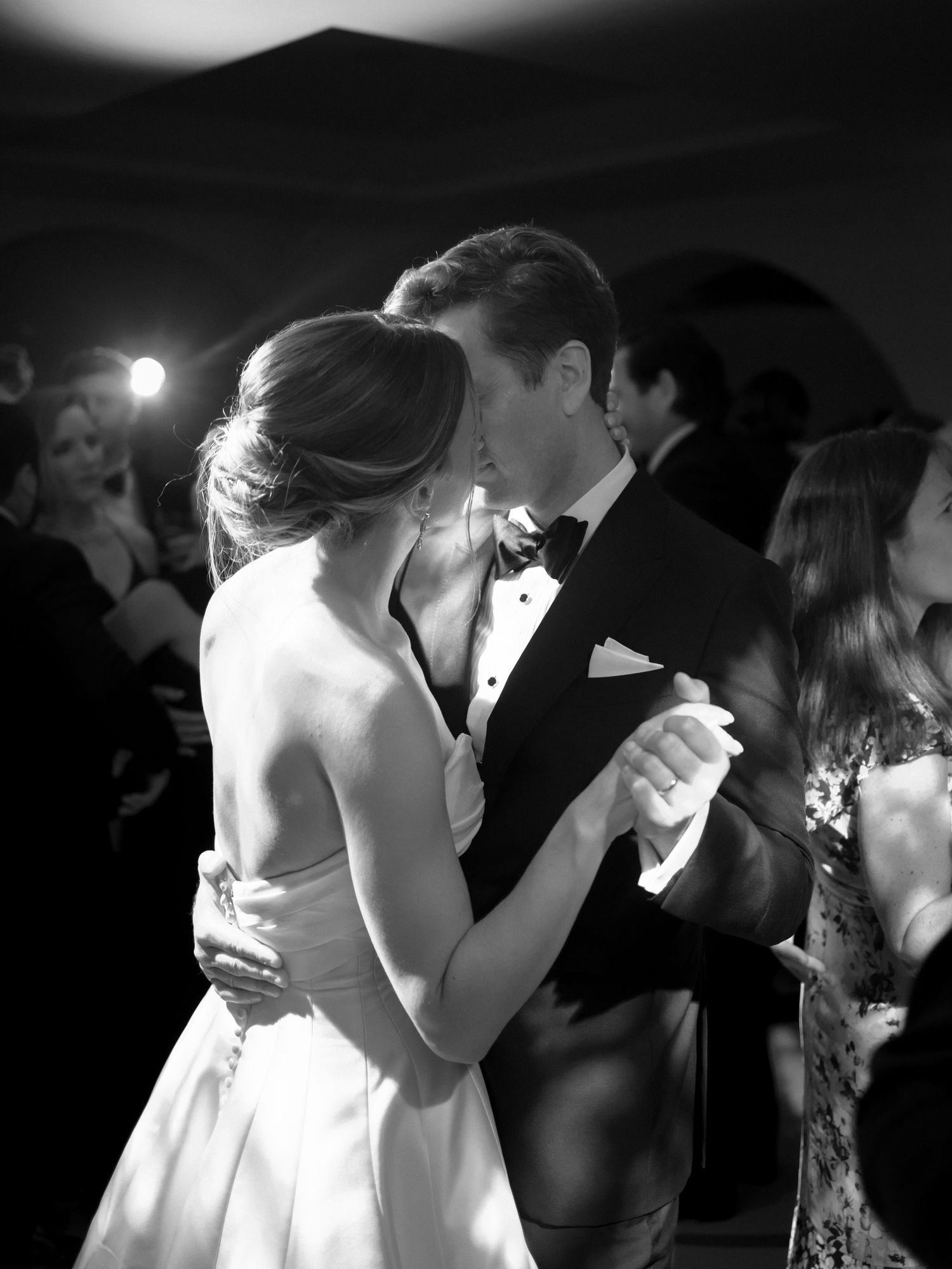 Bride and groom share an intimate first dance embrace at elegant black and white wedding reception.
