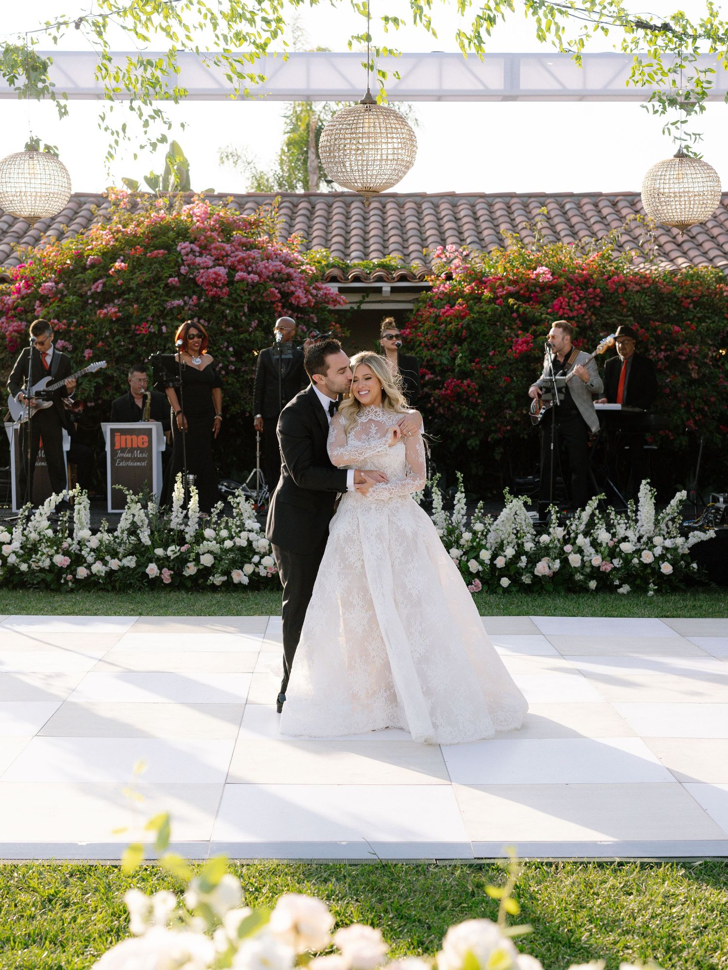 Bride and groom sharing their first dance on an outdoor dance floor with a live band.