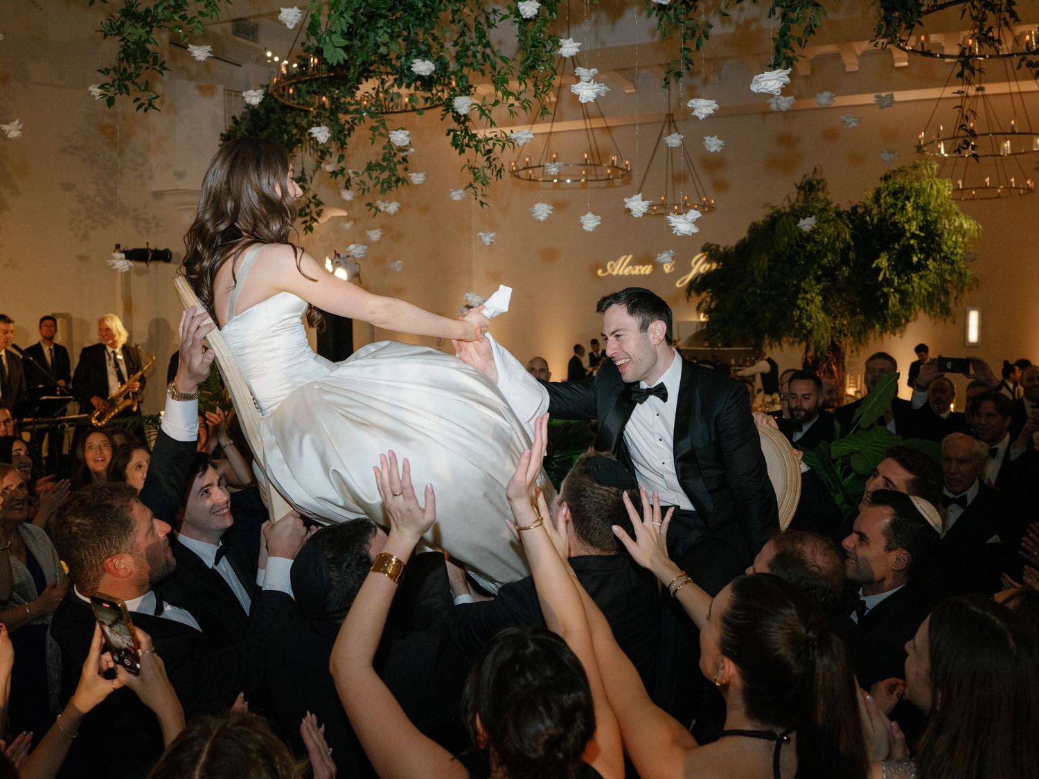 Bride being lifted by wedding guests during a celebratory hora dance at the reception.