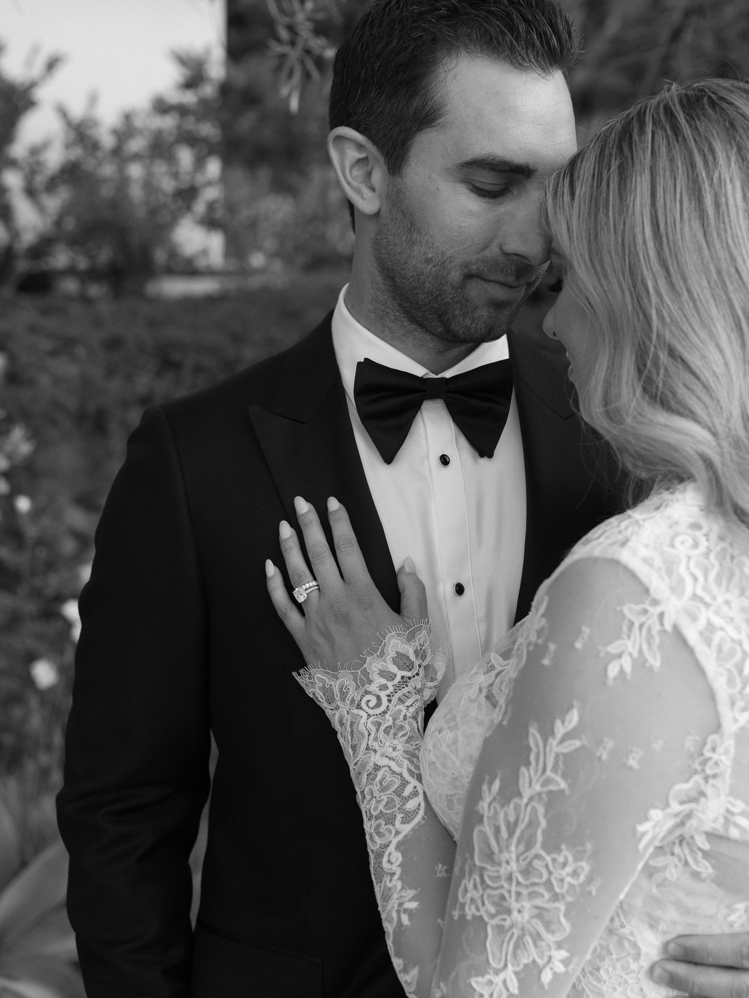 Black and white romantic portrait of a bride and groom in a close embrace outdoors.