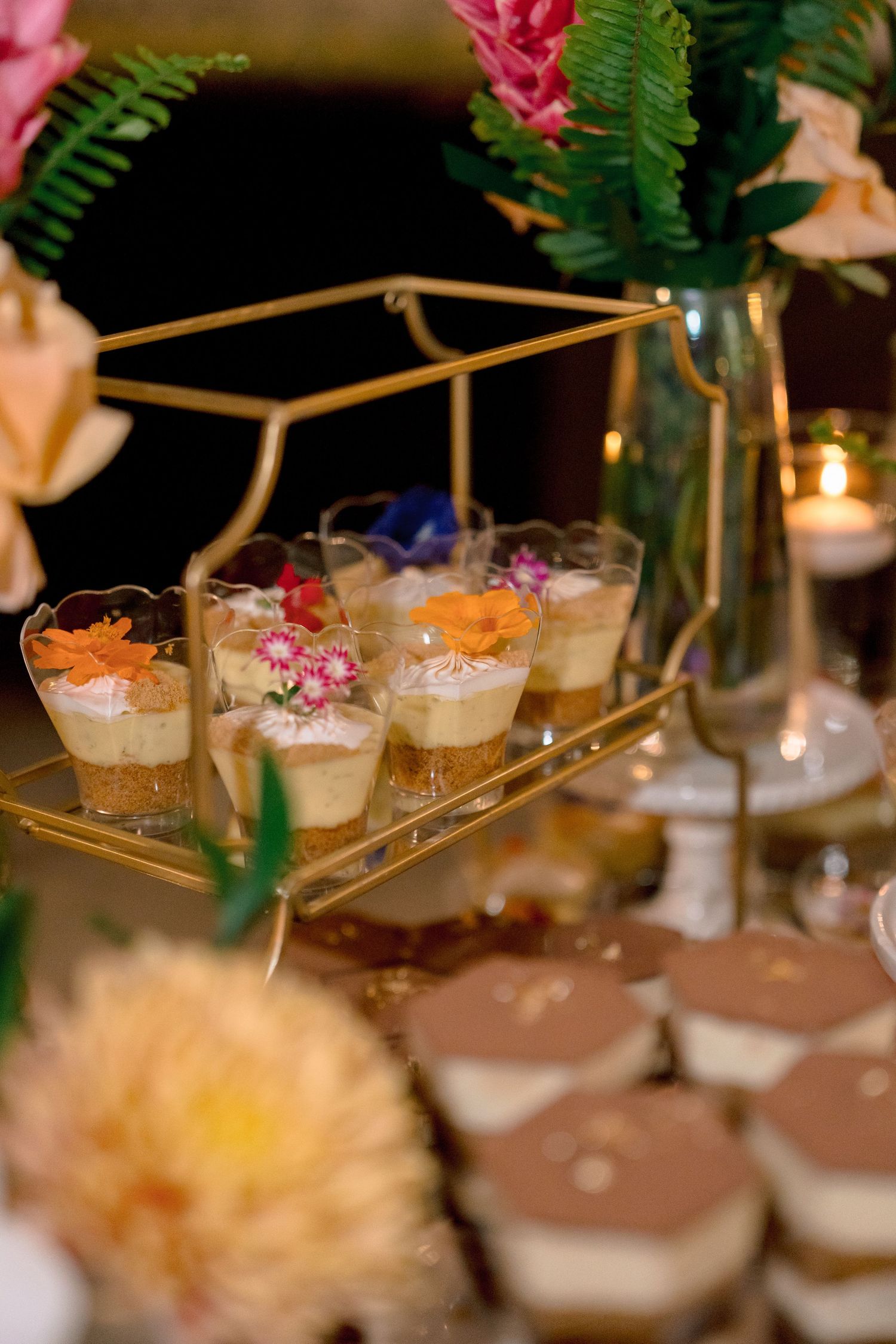 Elegant wedding dessert table with layered mousse cups and mini cakes on gold tiered stand.