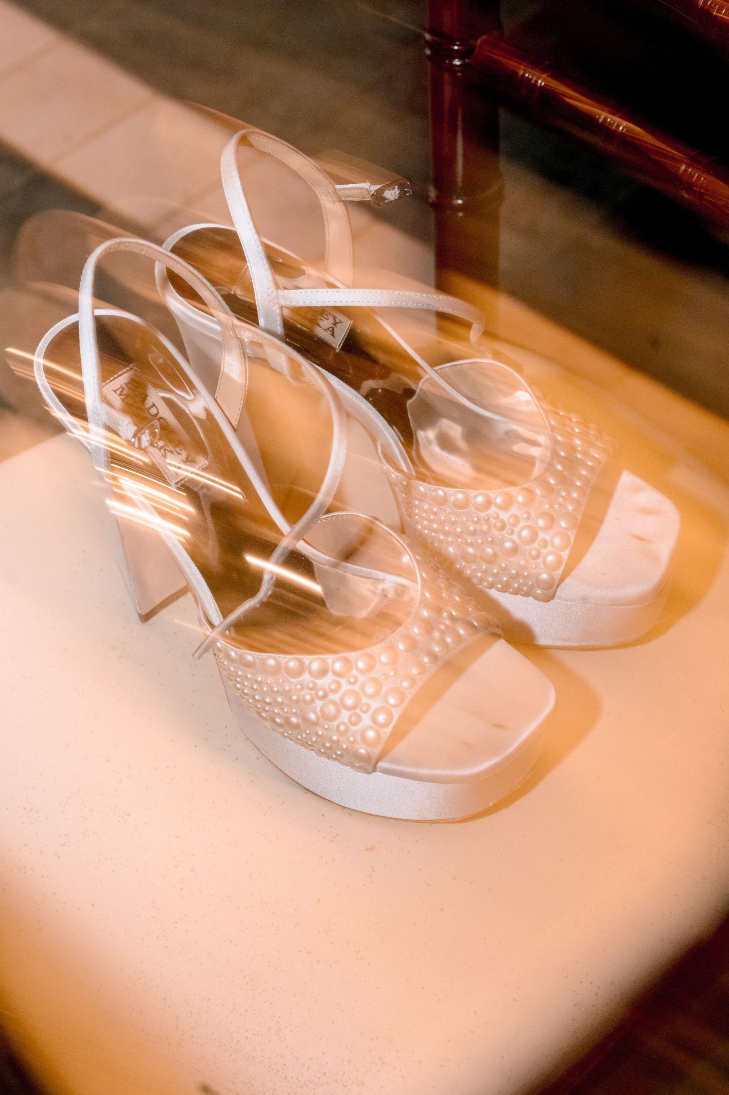 Elegant white bridal platform sandals with pearl embellishments and ankle straps displayed on a light surface.