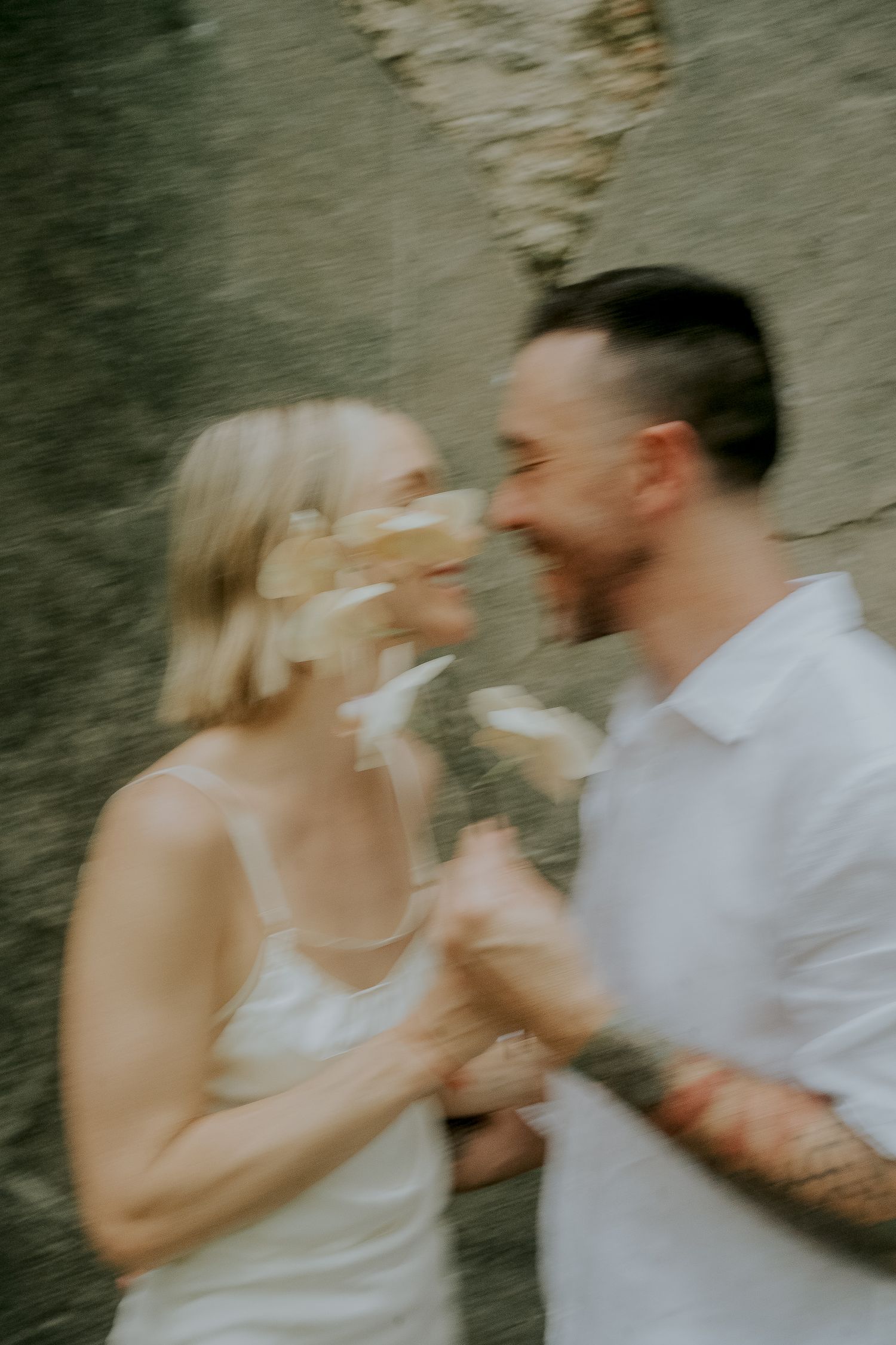 Blurred motion shot of a smiling couple holding white flowers, creating a dreamy romantic effect outdoors.
