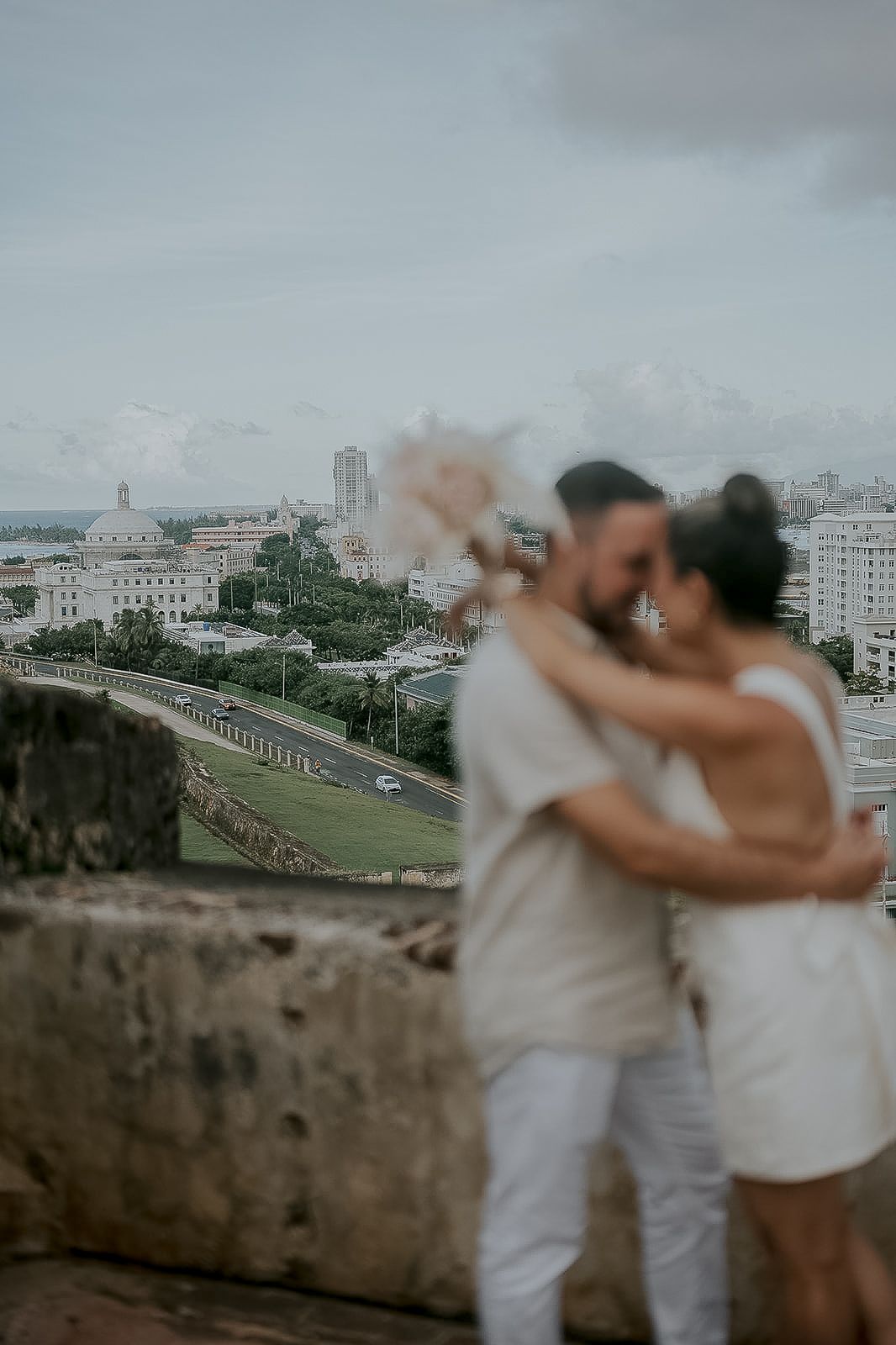 Couple embracing on ancient stone fortress walls with panoramic city views in the background.