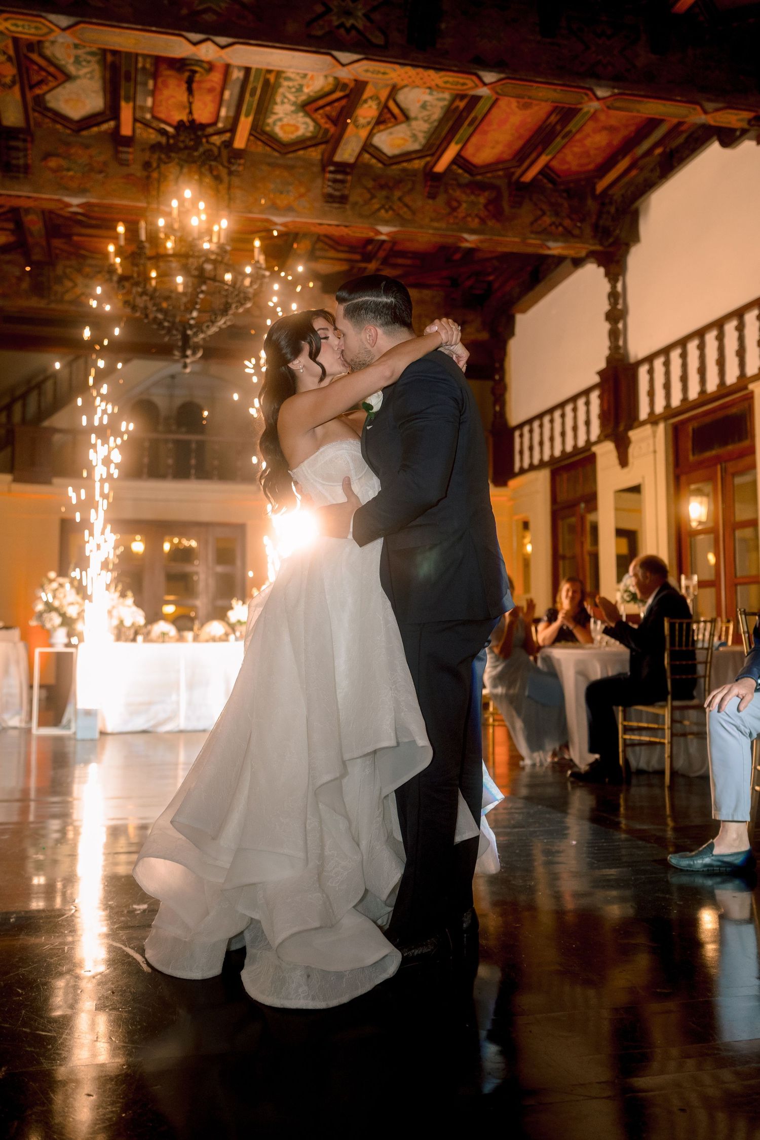 Couple sharing first dance with sparkling lights at wedding reception.