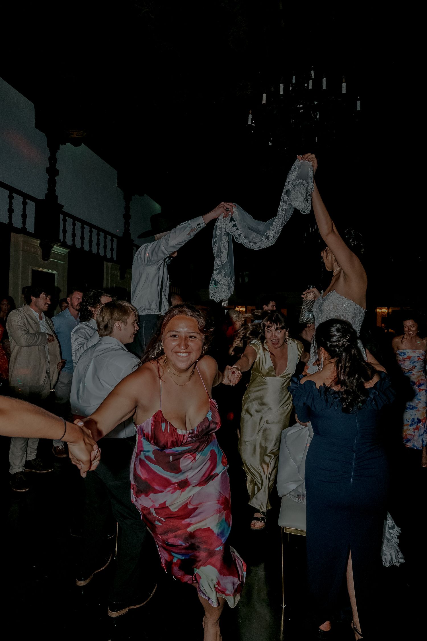 Wedding guests dance joyfully on the dance floor during reception.