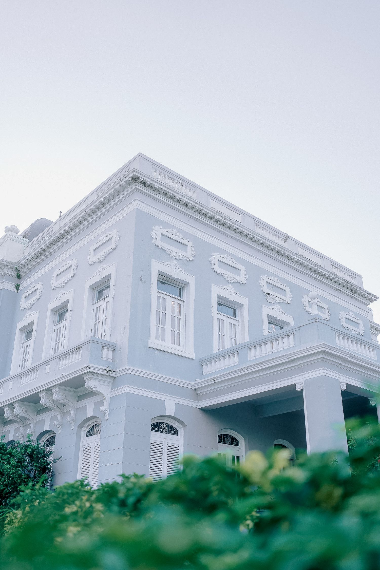 Elegant white neoclassical wedding venue exterior with ornate architectural details and lush greenery.