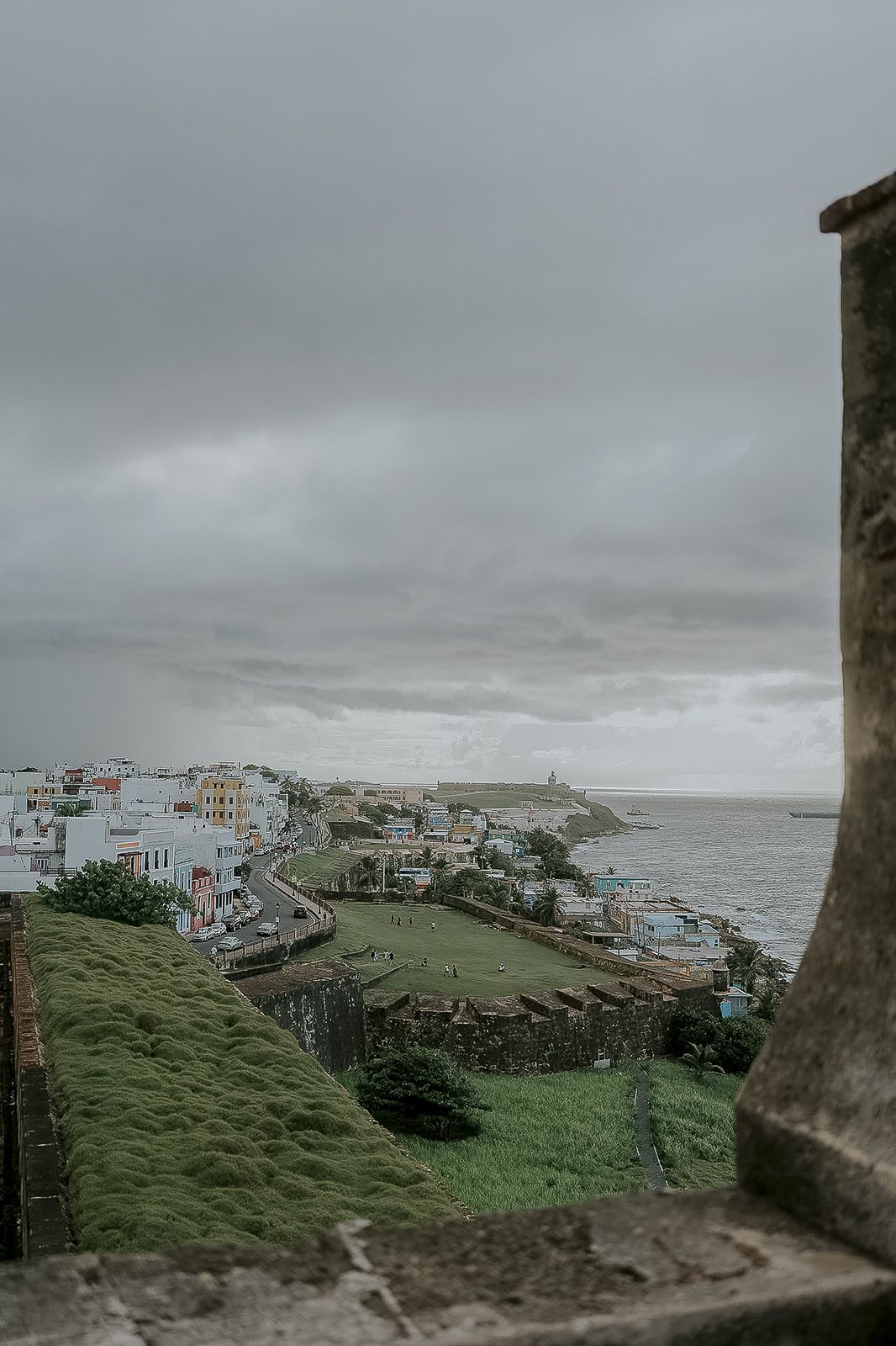 Aerial view of Old San Juan Puerto Rico coastline with colorful buildings moss-covered fortress walls and overcast sky.