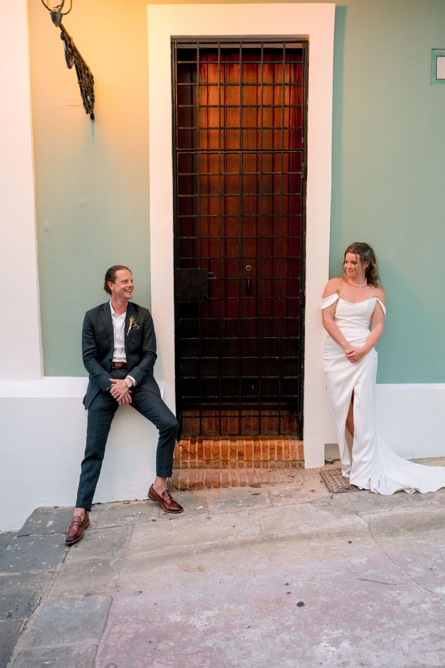Bride and groom pose beside colorful colonial doorway in Old San Juan wedding portrait.