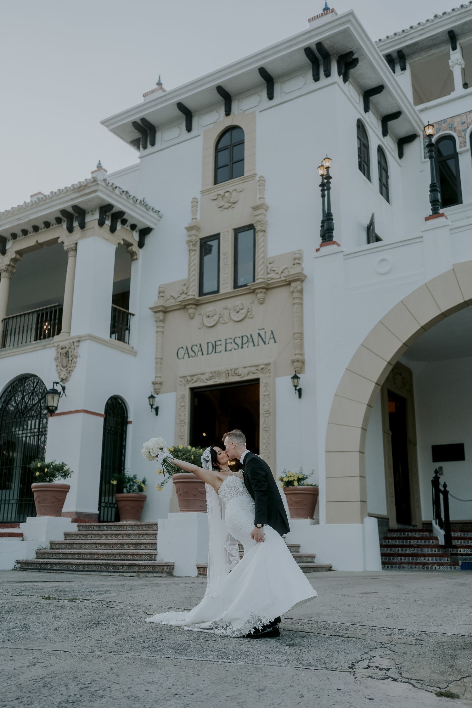 Bride and groom share romantic dip kiss outside Casa de España wedding venue in San Juan, Puerto Rico.