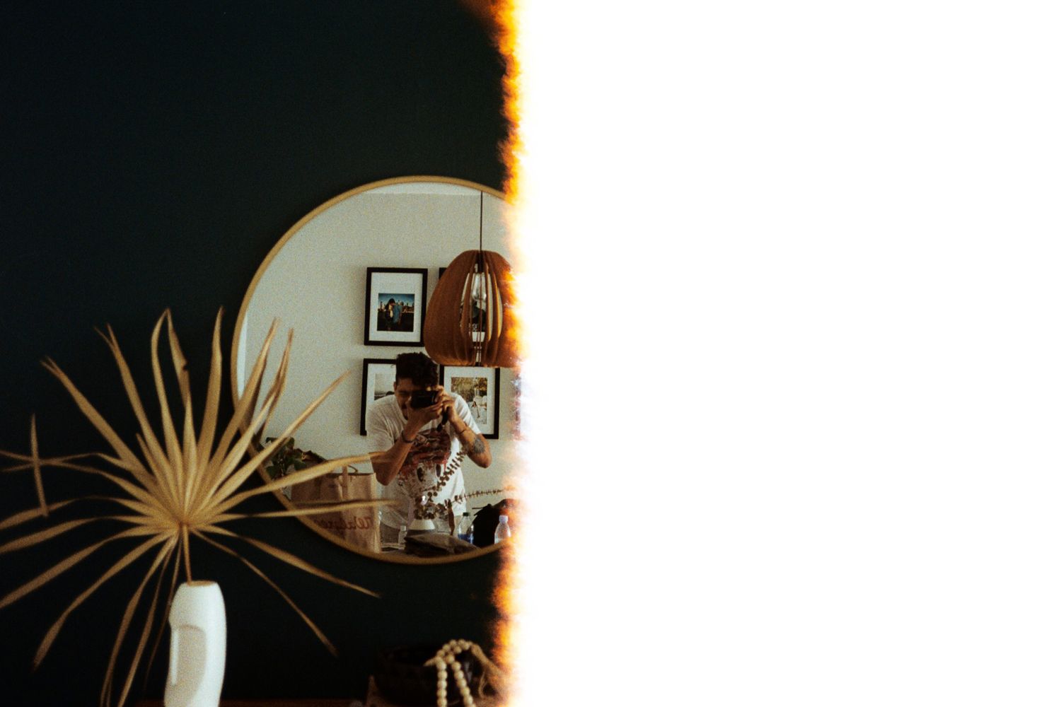 Bride captured in mirror reflection while getting ready in a warmly lit stylish room.