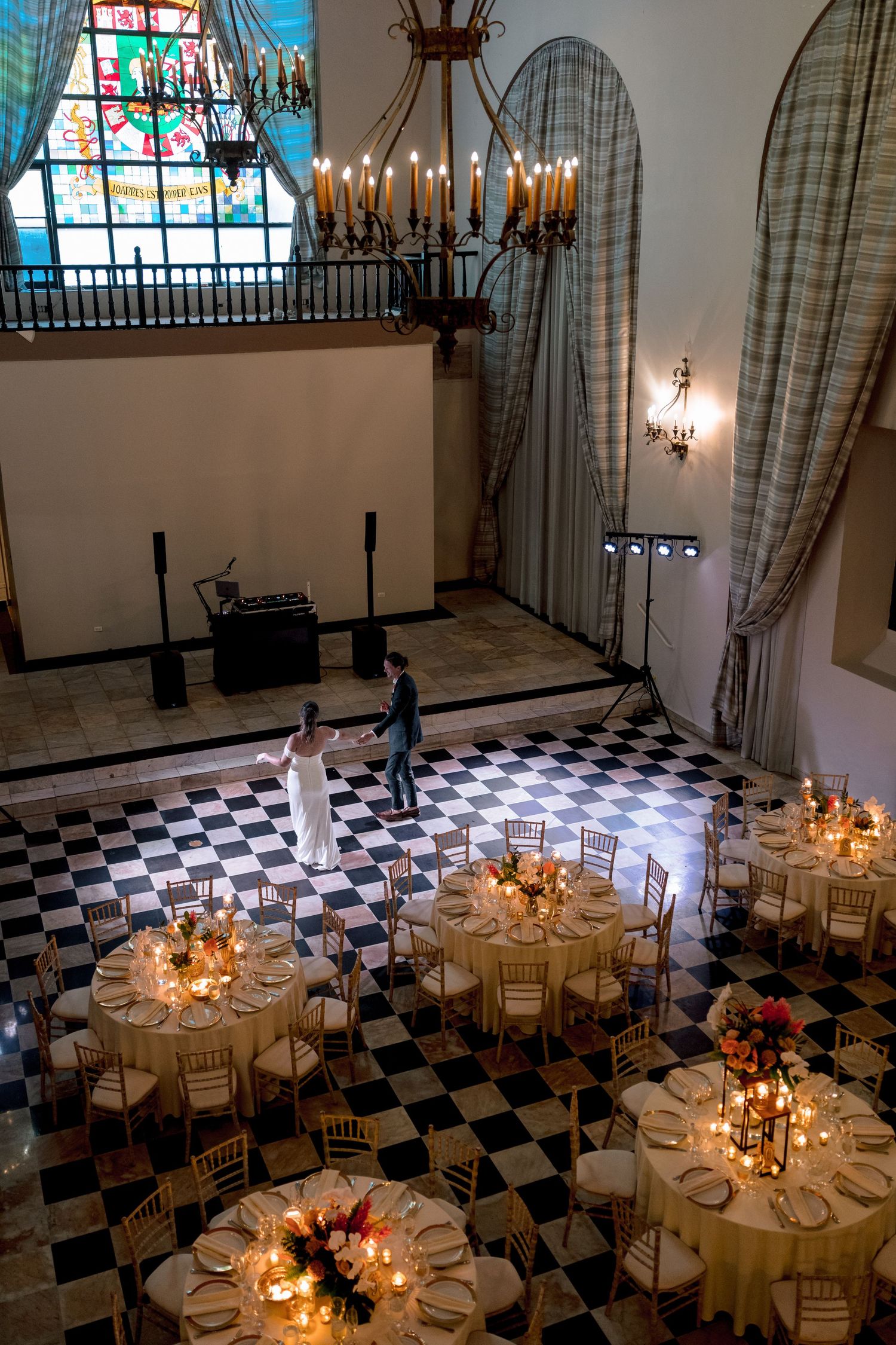 Aerial view of elegant wedding reception with checkered dance floor, round tables, and candlelight.