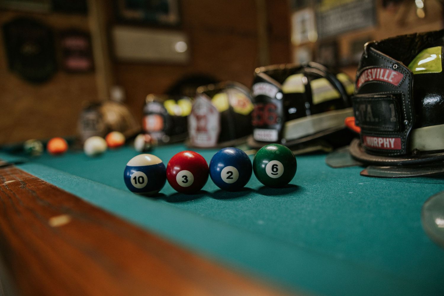 Billiard balls numbered 10, 1, 2, and 6 arranged on a green pool table in a dimly lit bar.
