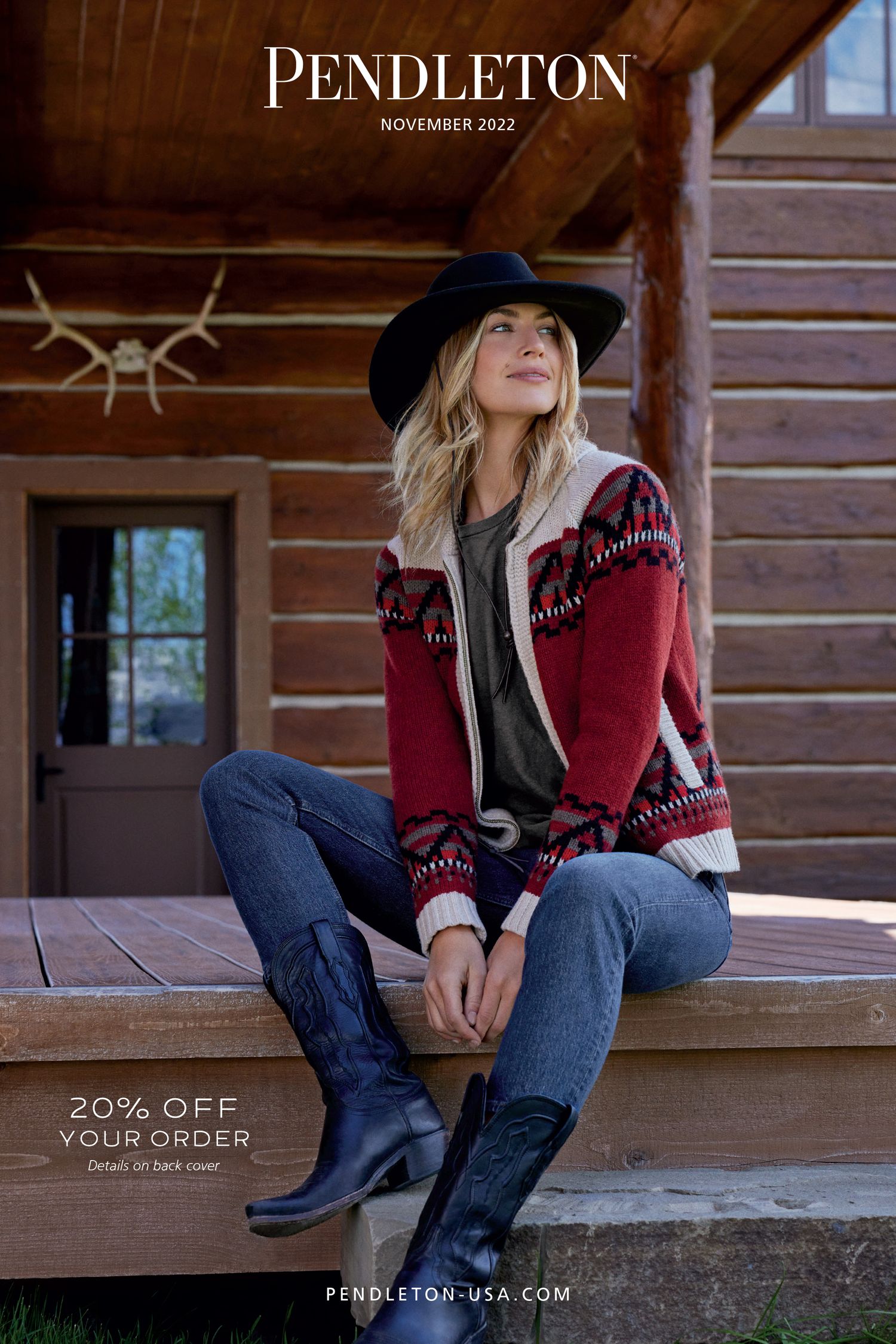 Woman in a wide-brim hat and Pendleton red patterned cardigan sitting on a rustic cabin porch.