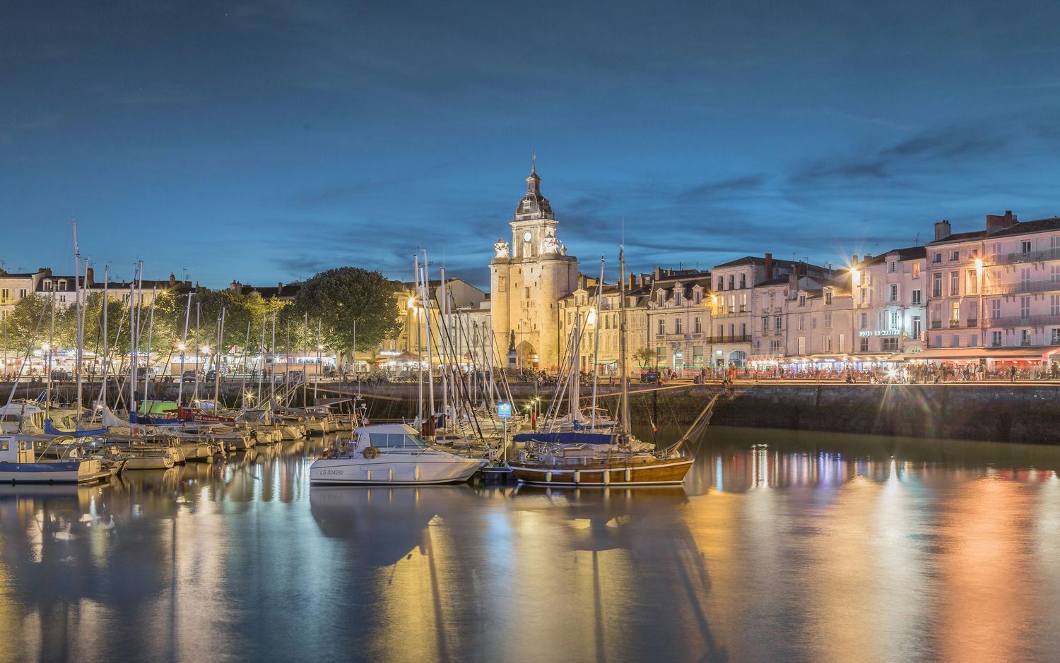 Vieux port de La Rochelle au crépuscule, bâtiments historiques illuminés et bateaux