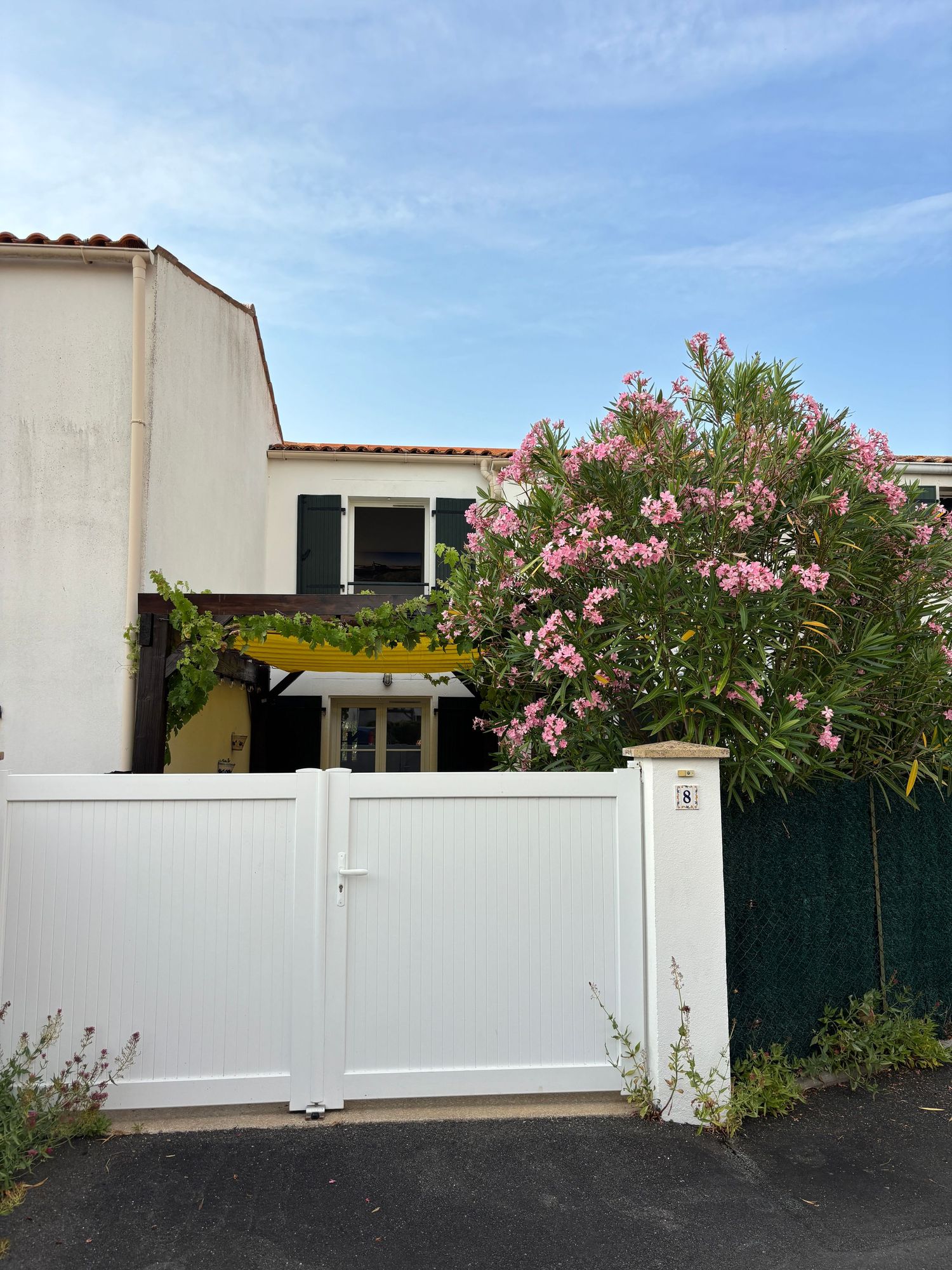 Portail blanc de la maison des Carrelets à Fouras, laurier-rose et pergola jaune en arrière plan