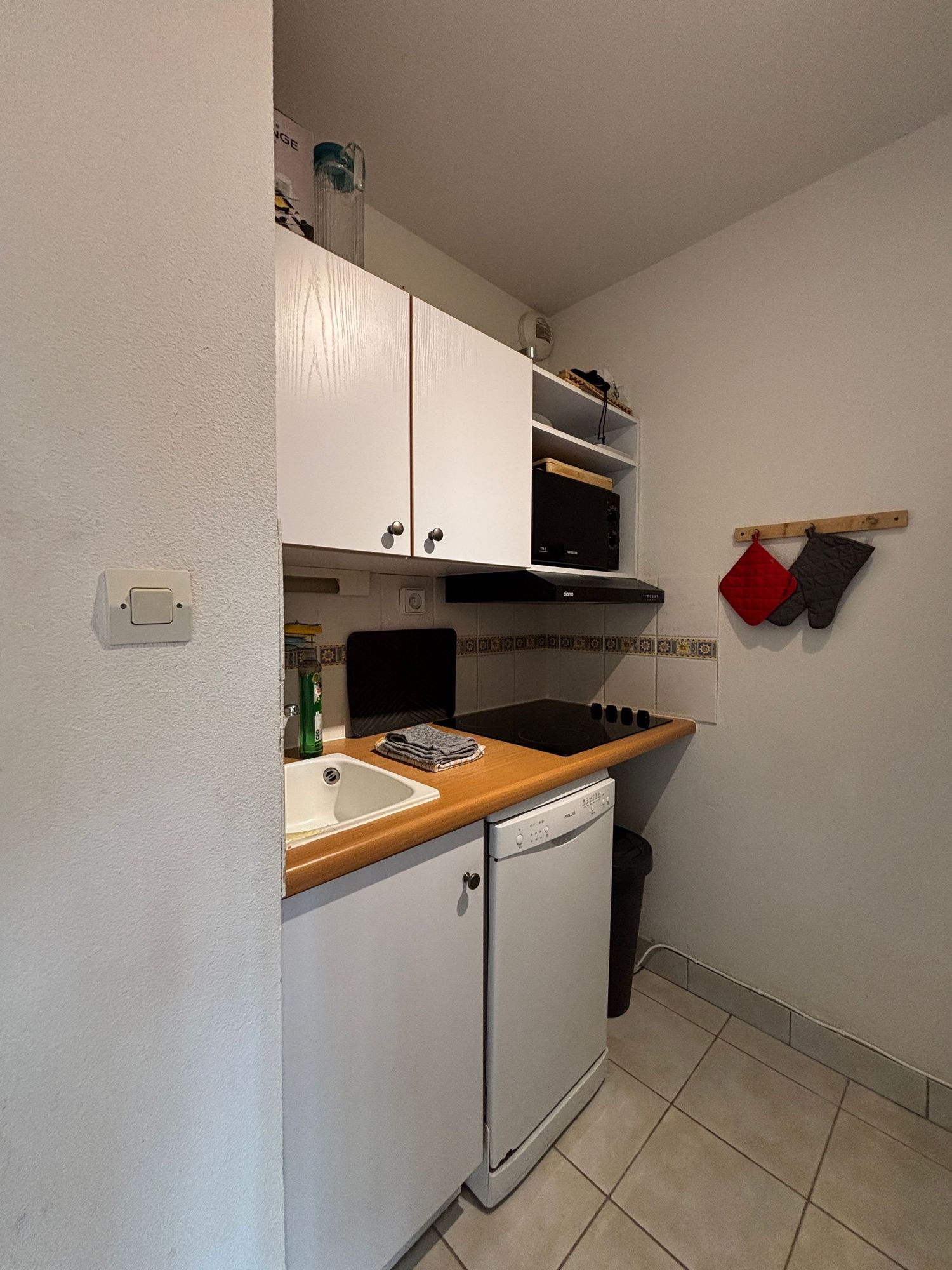 Kitchenette blanche compacte avec plan de travail en bois et appareils intégrés