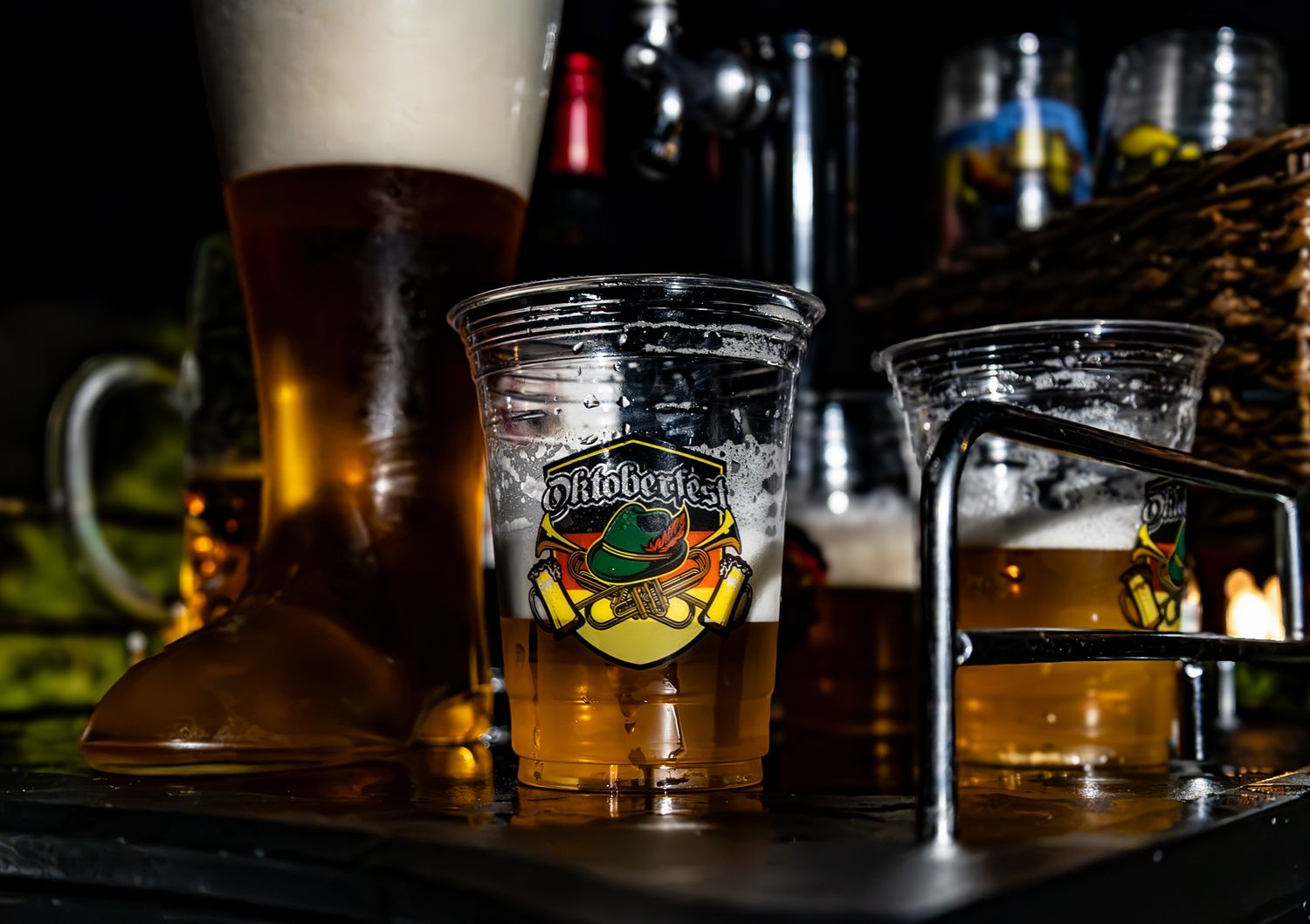 Harp lager beer served in branded plastic cups on a bar tray with pint glasses in the background.