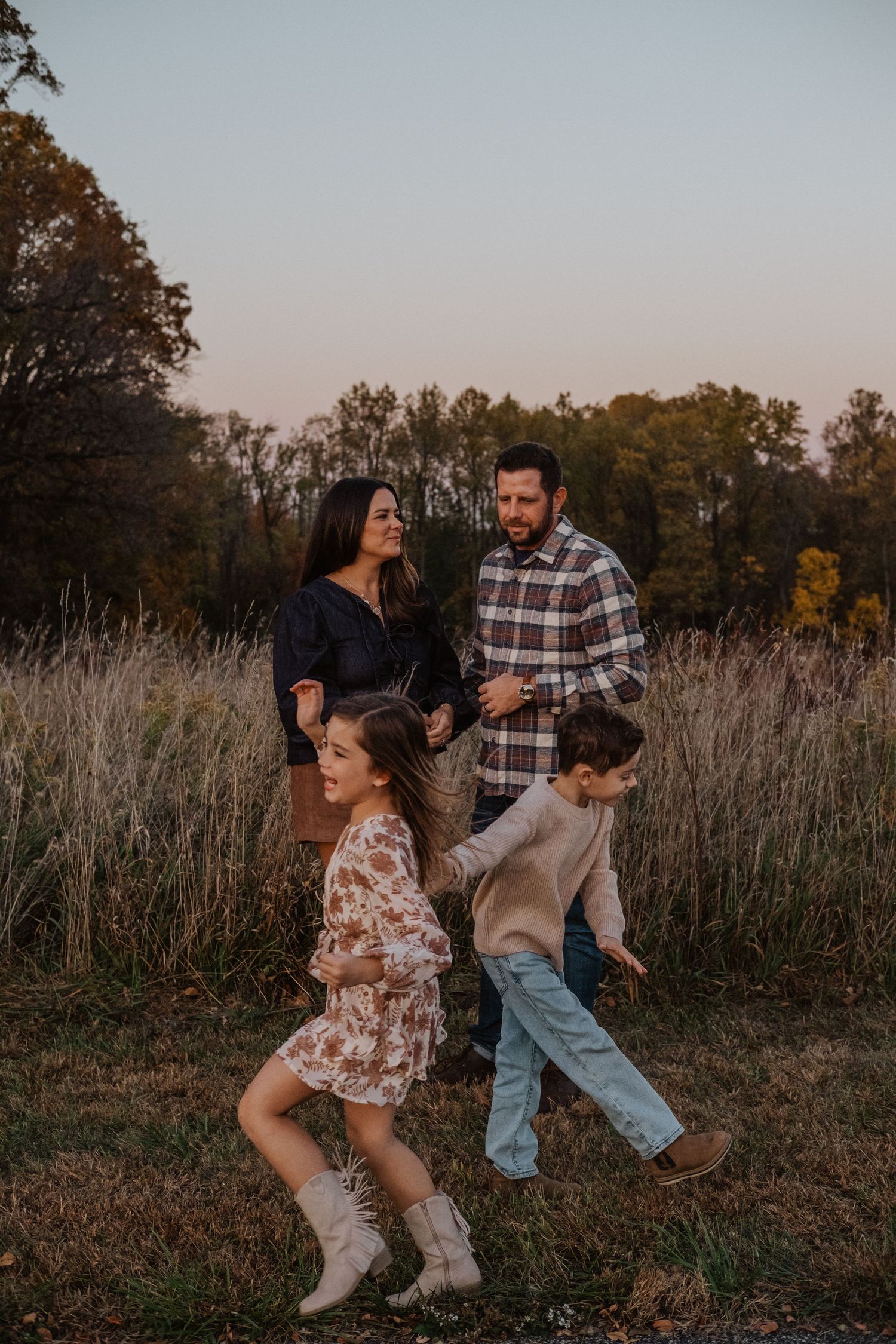 Family of four enjoying a golden hour walk in an autumn field.