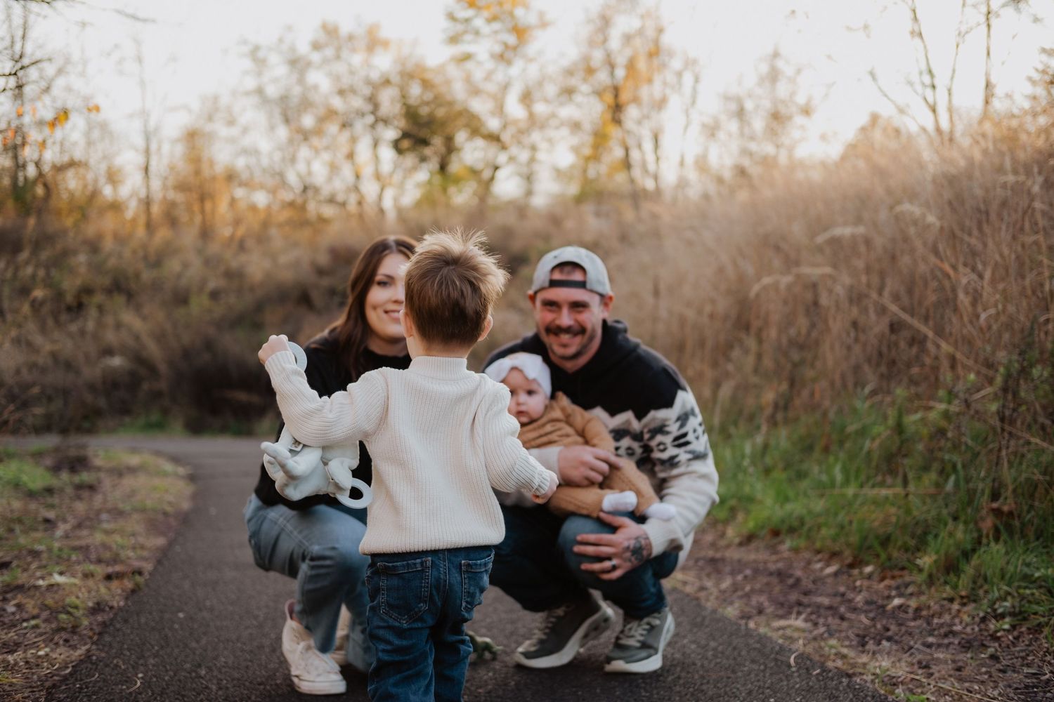 Young family with two small children sharing a joyful moment on a scenic autumn path.