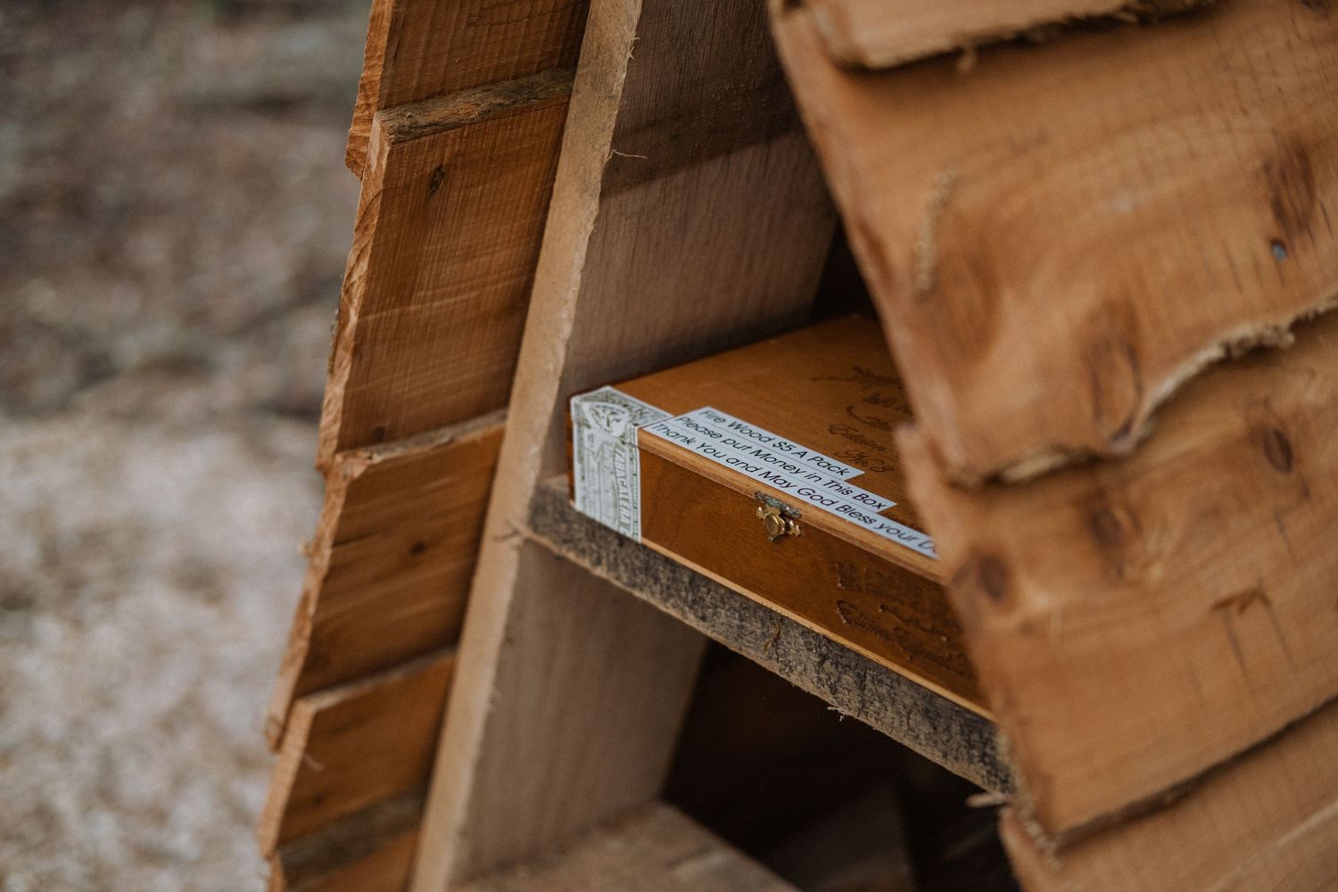 A wooden ruler resting on a shelf inside a rustic triangular wooden structure outdoors.