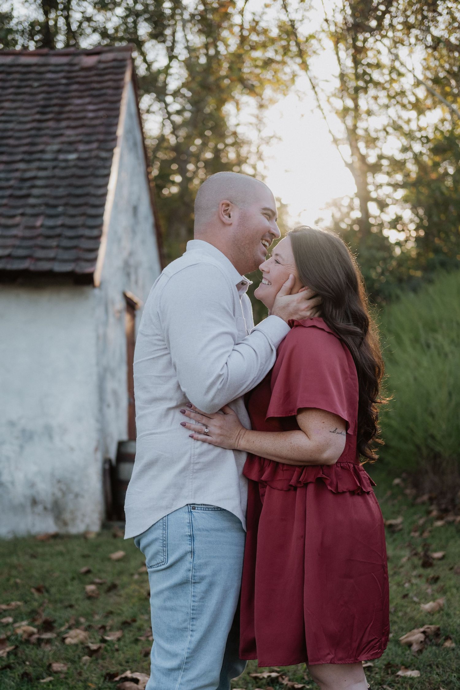Couple sharing a romantic moment near a rustic building at golden hour.