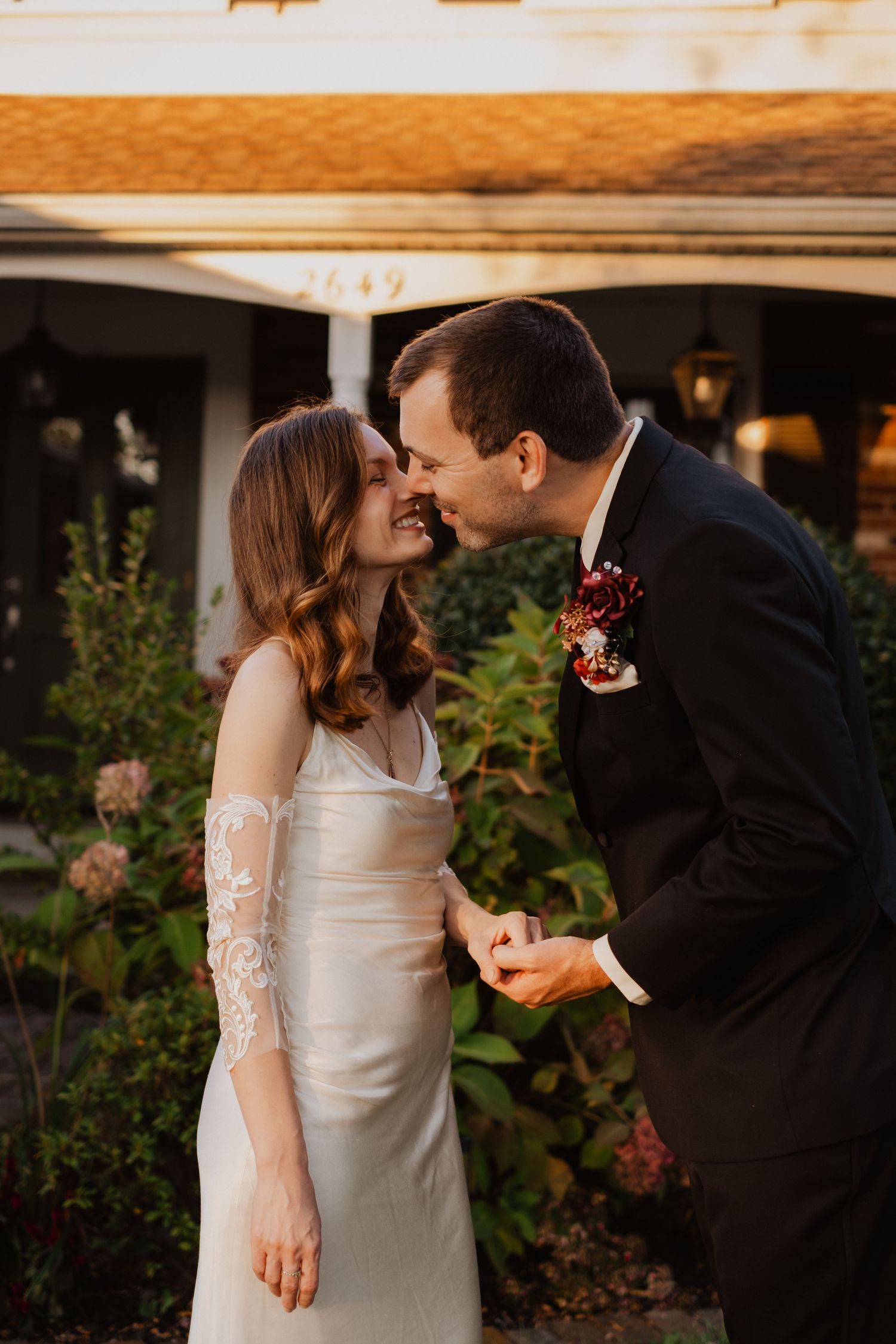Bride and groom sharing an intimate moment outside a home at golden hour.