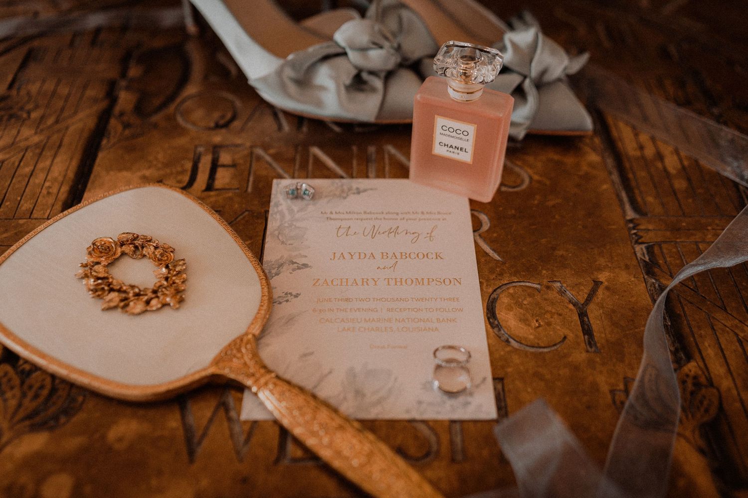 Wedding flat lay with floral invitation, vintage hand mirror, perfume bottle, and bridal accessories.