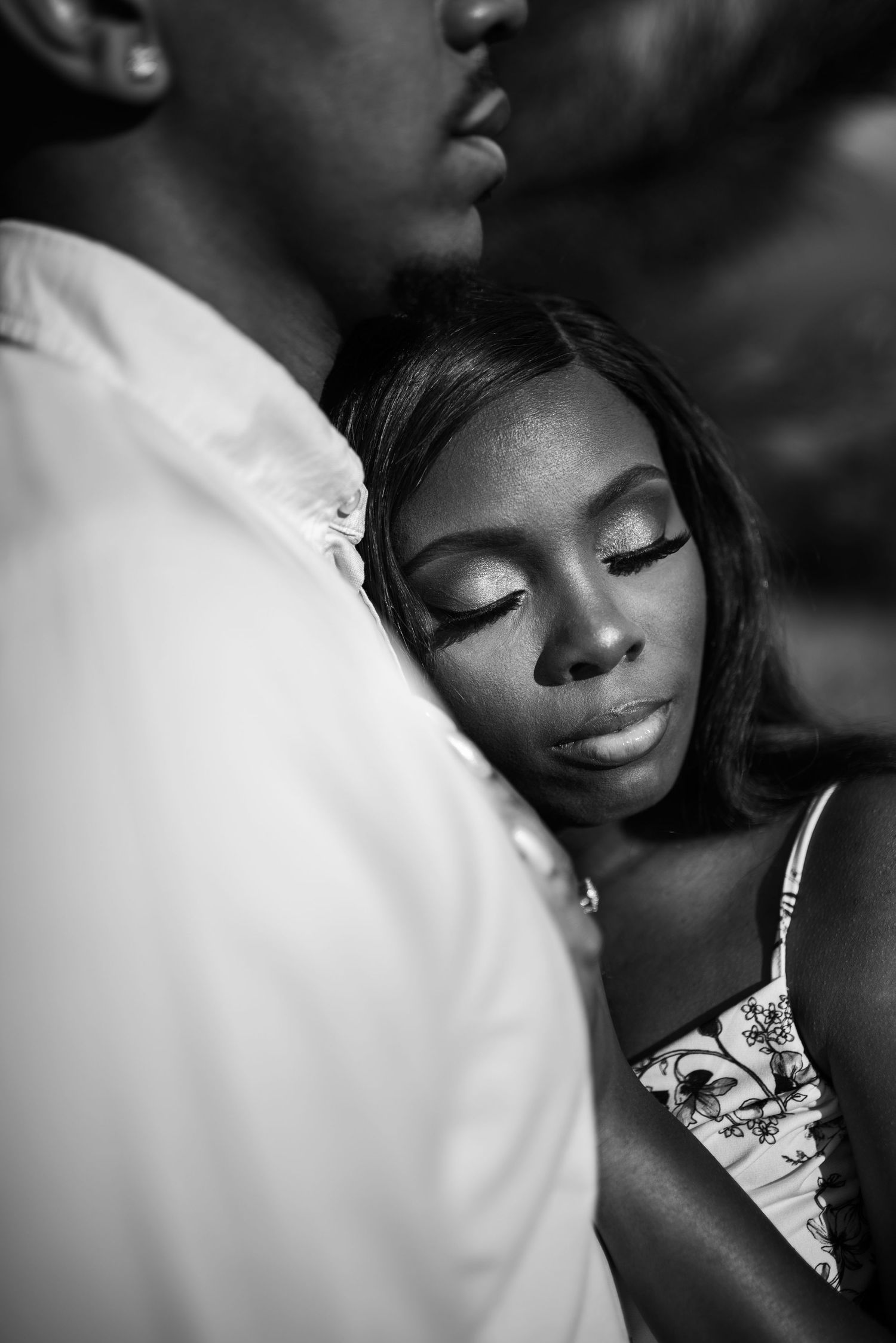 Black and white photo of a woman resting her head on a mans chest with eyes closed in a tender romantic moment.
