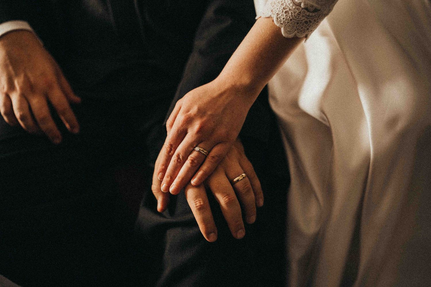 Close-up of bride and groom hands showing gold wedding rings on their wedding day.