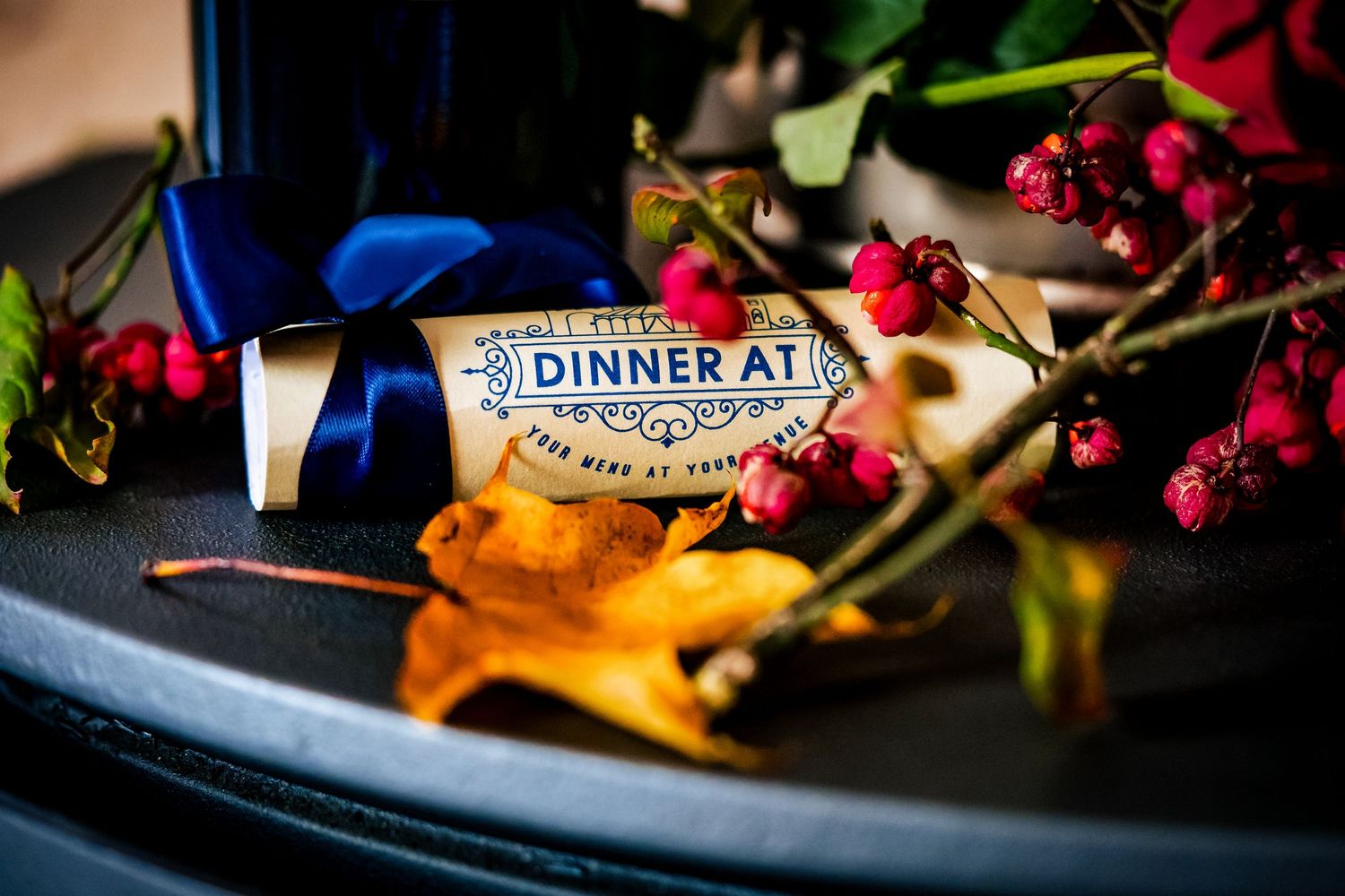 Elegant Dinner At chocolate bar with blue ribbon, red berries, and autumn leaves on a dark plate.