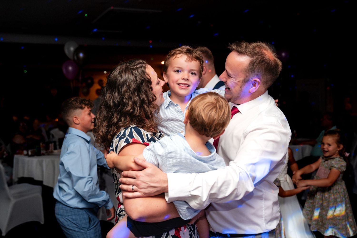 Family embracing and smiling joyfully at a wedding reception celebration event.