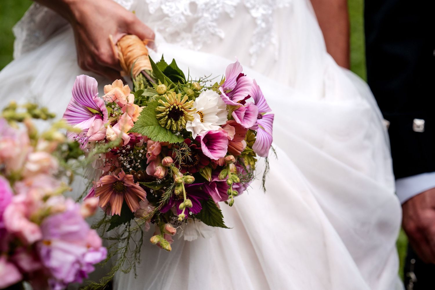 Bride in white wedding dress holding a colorful bouquet of pink, purple, and green wildflowers.