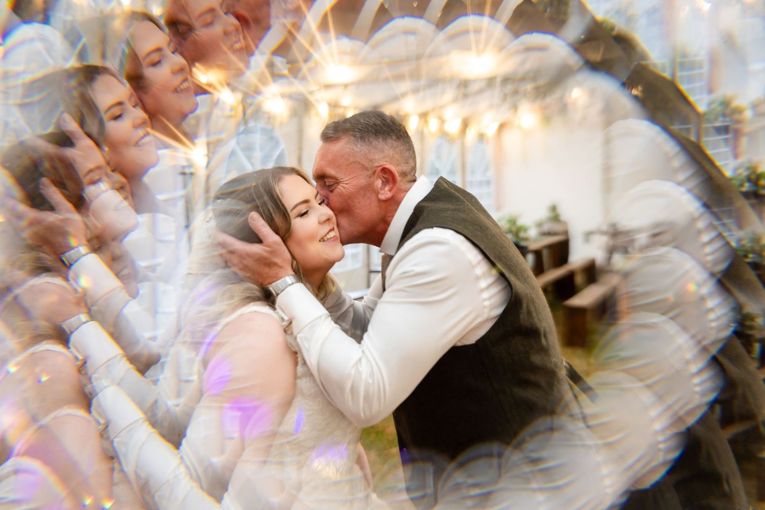 A couple shares a romantic first dance kiss surrounded by dreamy bubble bokeh at their elegant wedding reception.