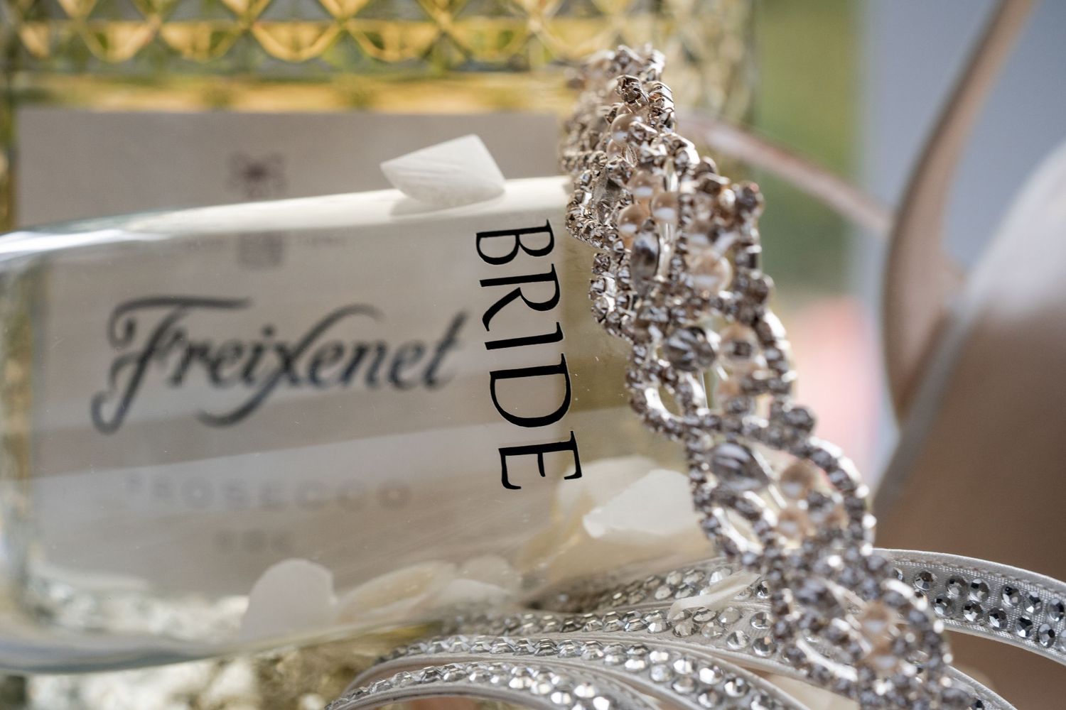 Elegant bridal tiara with sparkling crystals displayed next to a Freixenet bottle and a Bride label at a wedding celebration.