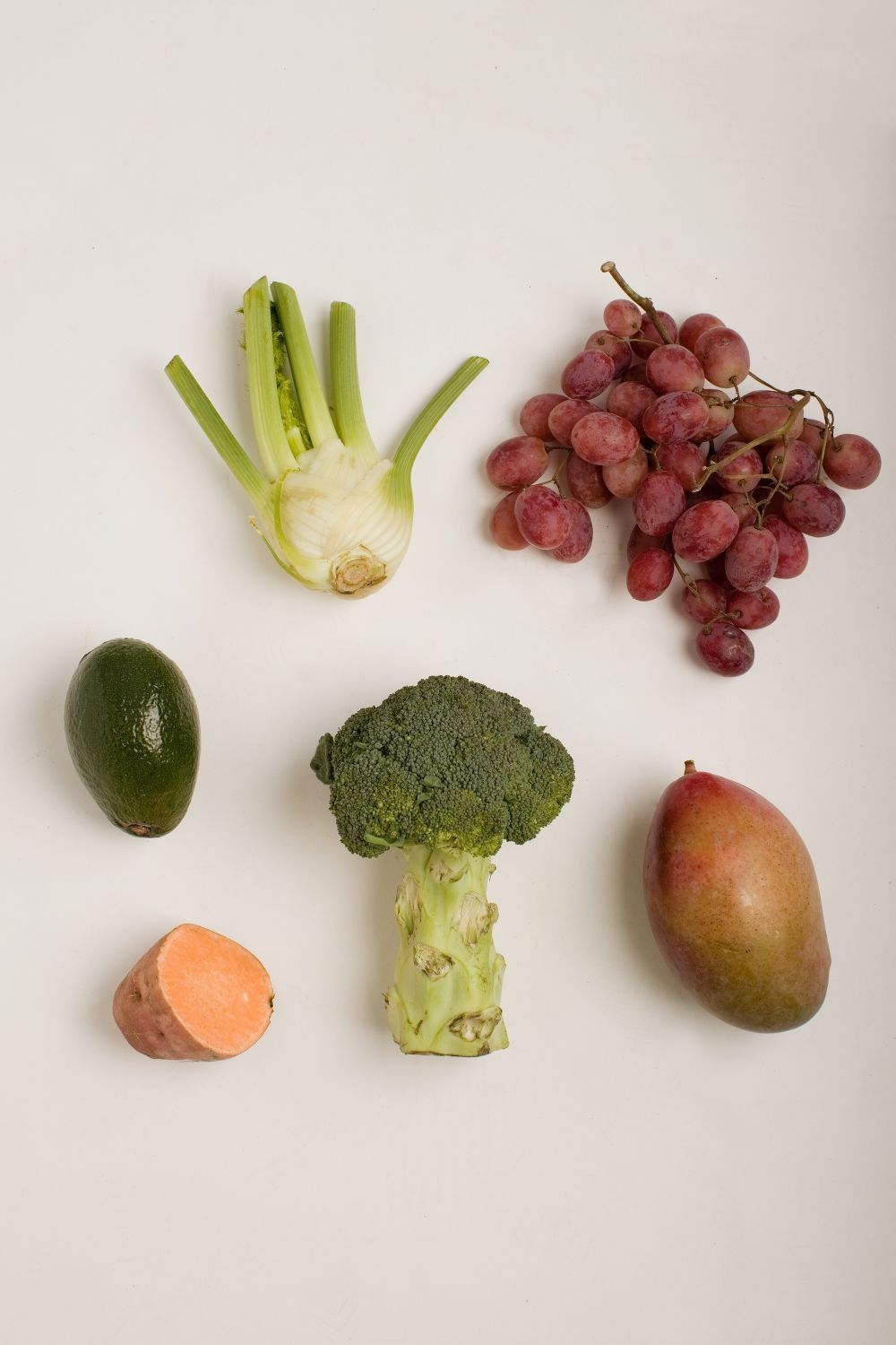 Composition à plat de légumes et de fruits frais, notamment du fenouil, du brocoli, du raisin, de l'avocat, de la mangue en studio.