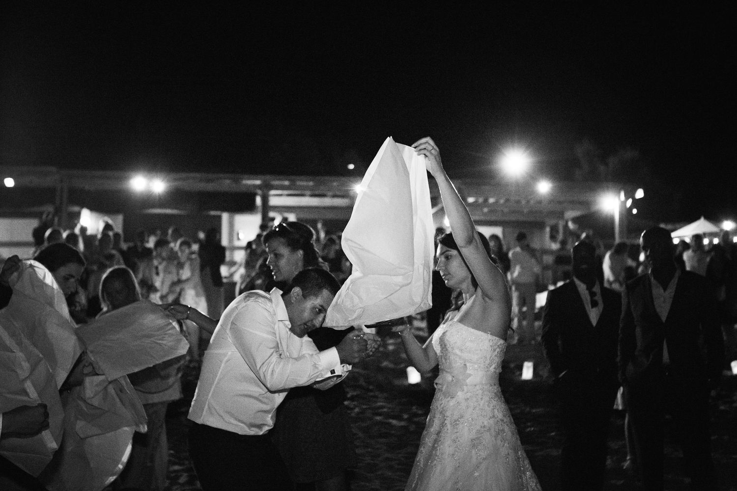 Photo de danse de mariage en noir et blanc, montrant les mariés dansant sous le voile levé lors d'une réception nocturne en extérieur.