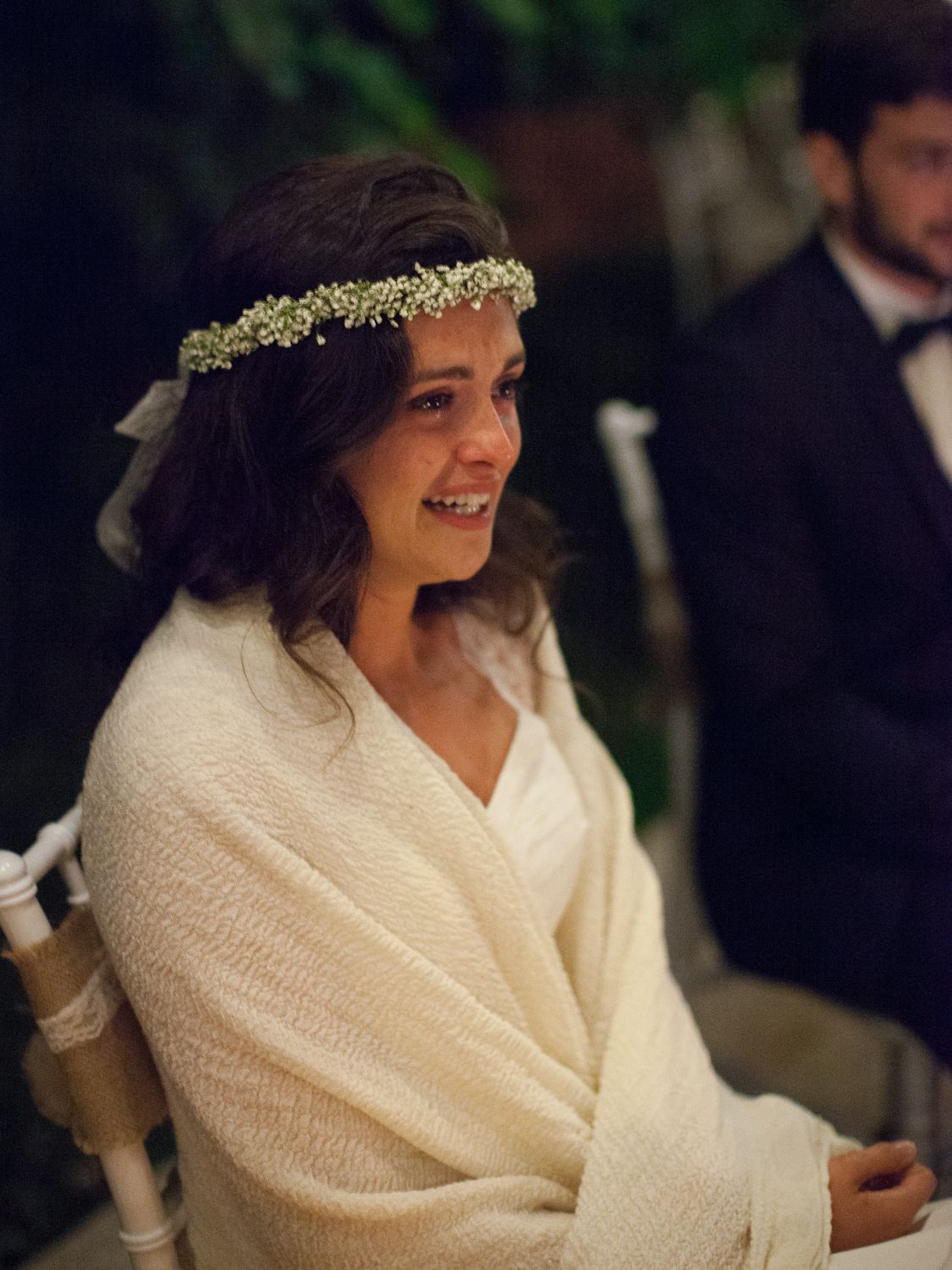 Une mariée souriante, coiffée d'une couronne de fleurs et vêtue d'un châle blanc, lors de la cérémonie de mariage à Corte