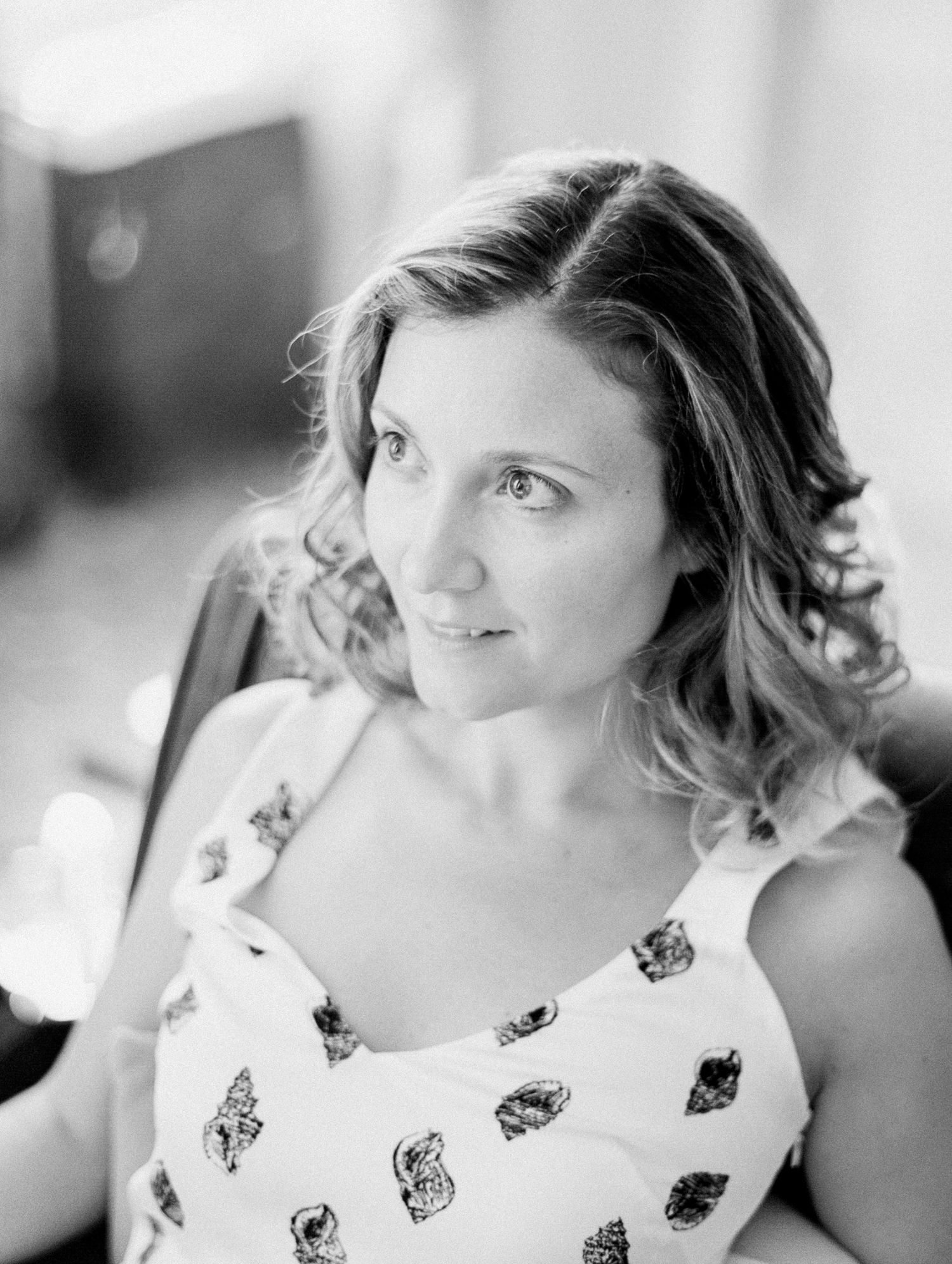 Black and white portrait of a young woman in a floral dress, gazing thoughtfully to the side.