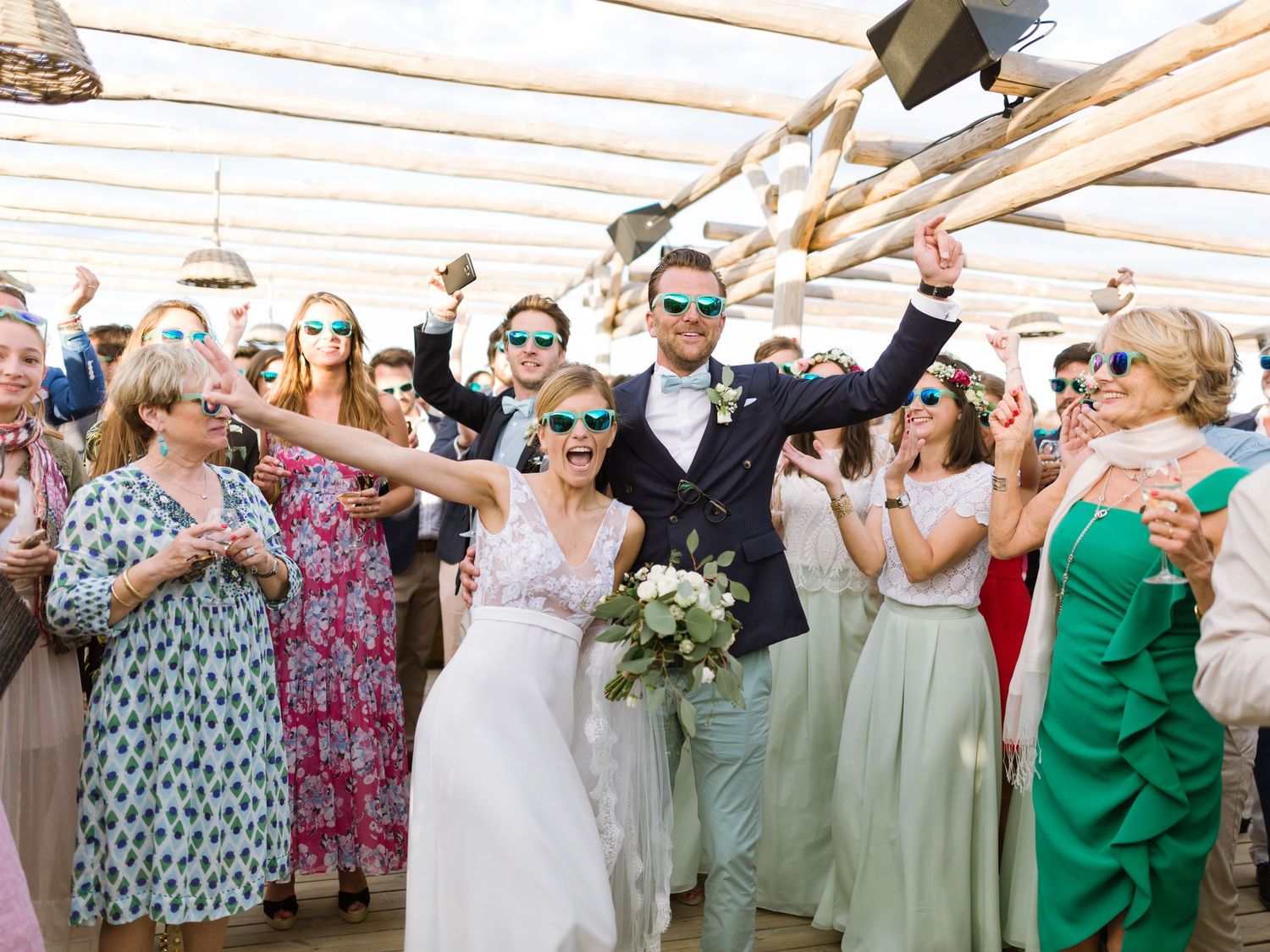 Les jeunes mariés, rayonnants de bonheur, célèbrent leur mariage avec leurs invités, lunettes de soleil sur le nez, lors d'une réception
