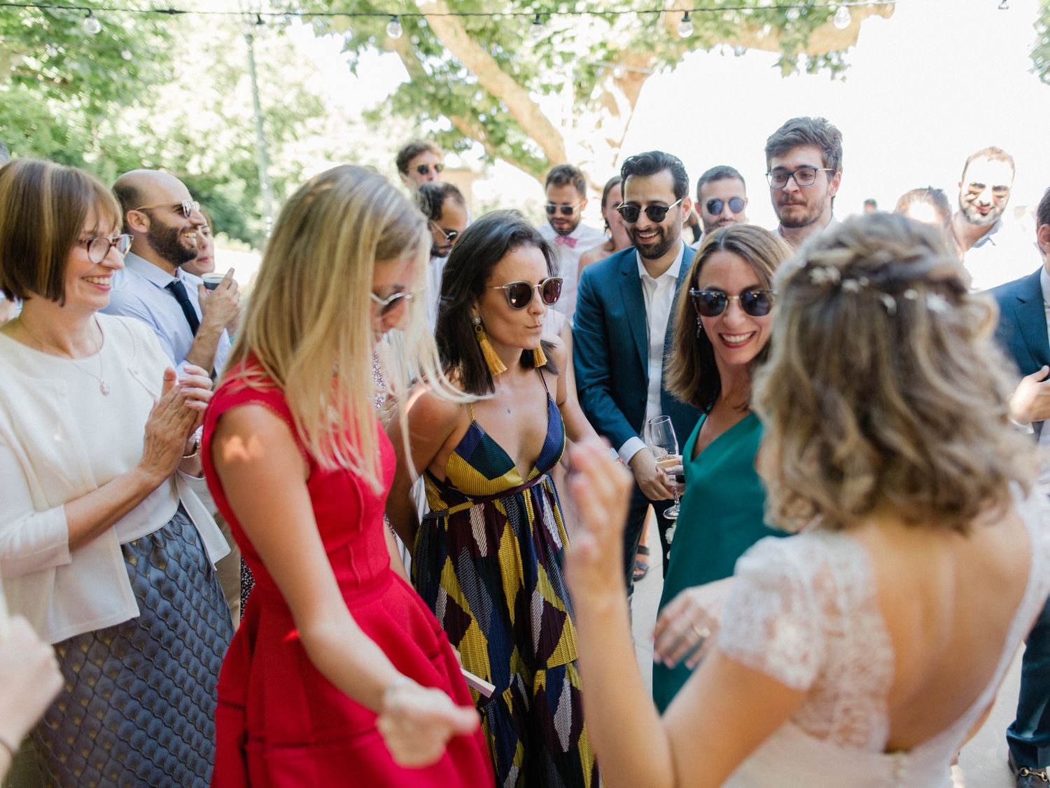 Guests dancing and celebrating at an outdoor wedding reception surrounded by trees and greenery.