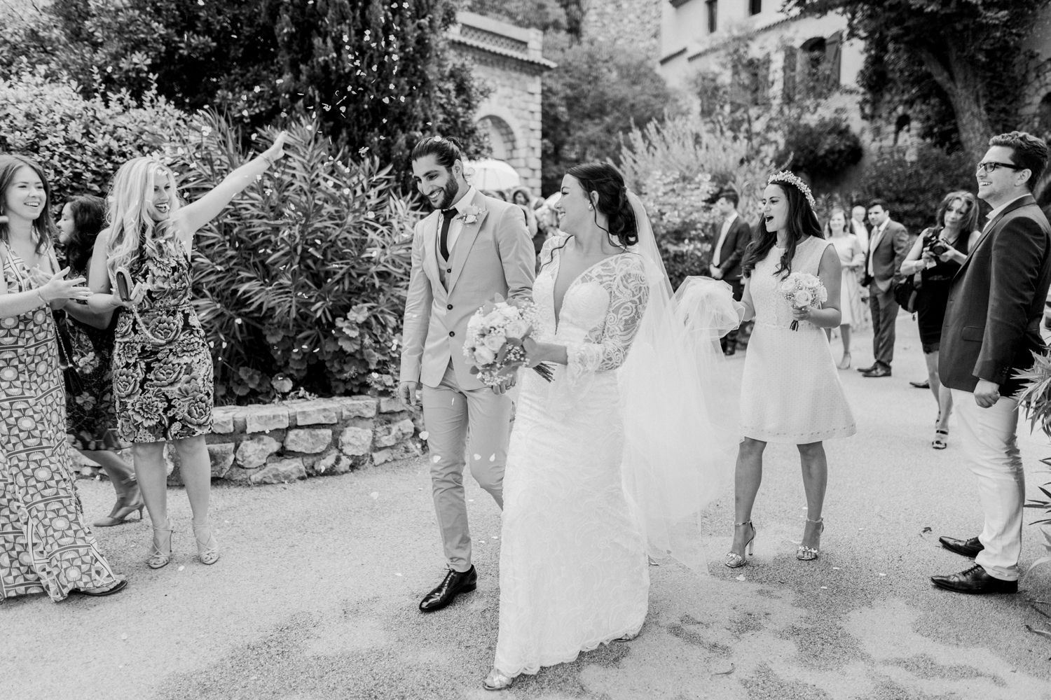 Photo en noir et blanc d'une mariée et d'un marié s'embrassant tandis que les invités célèbrent l'événement lors d'une cérémonie de mariage
