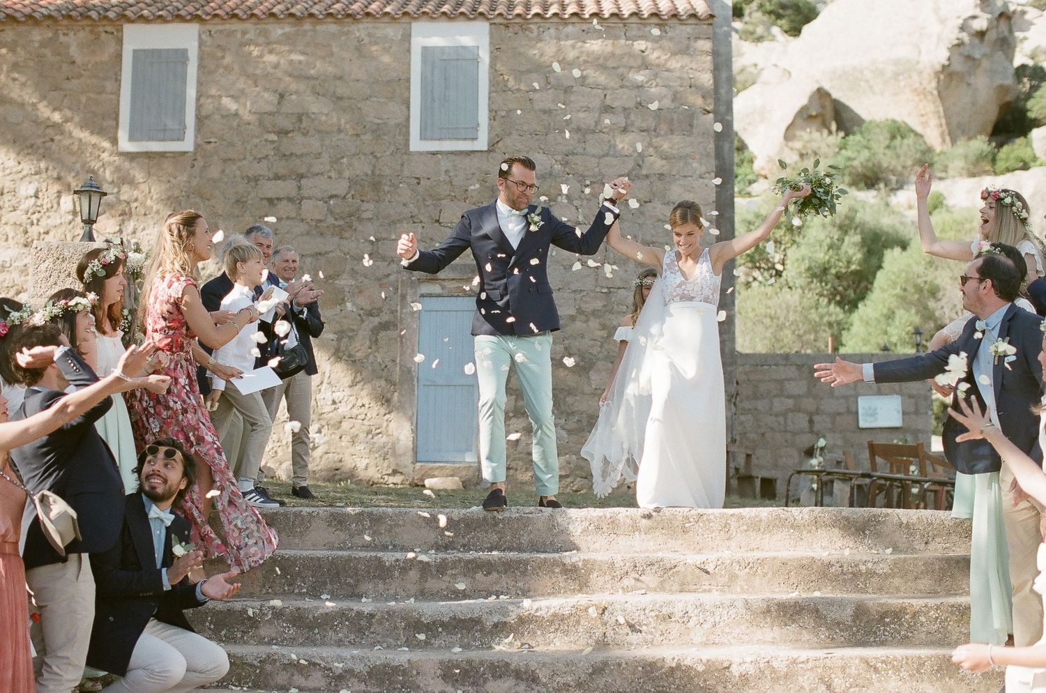 Les jeunes mariés sortent de la chapelle en pierre sous les jets de confettis des invités, lors d'une joyeuse célébration de mariage