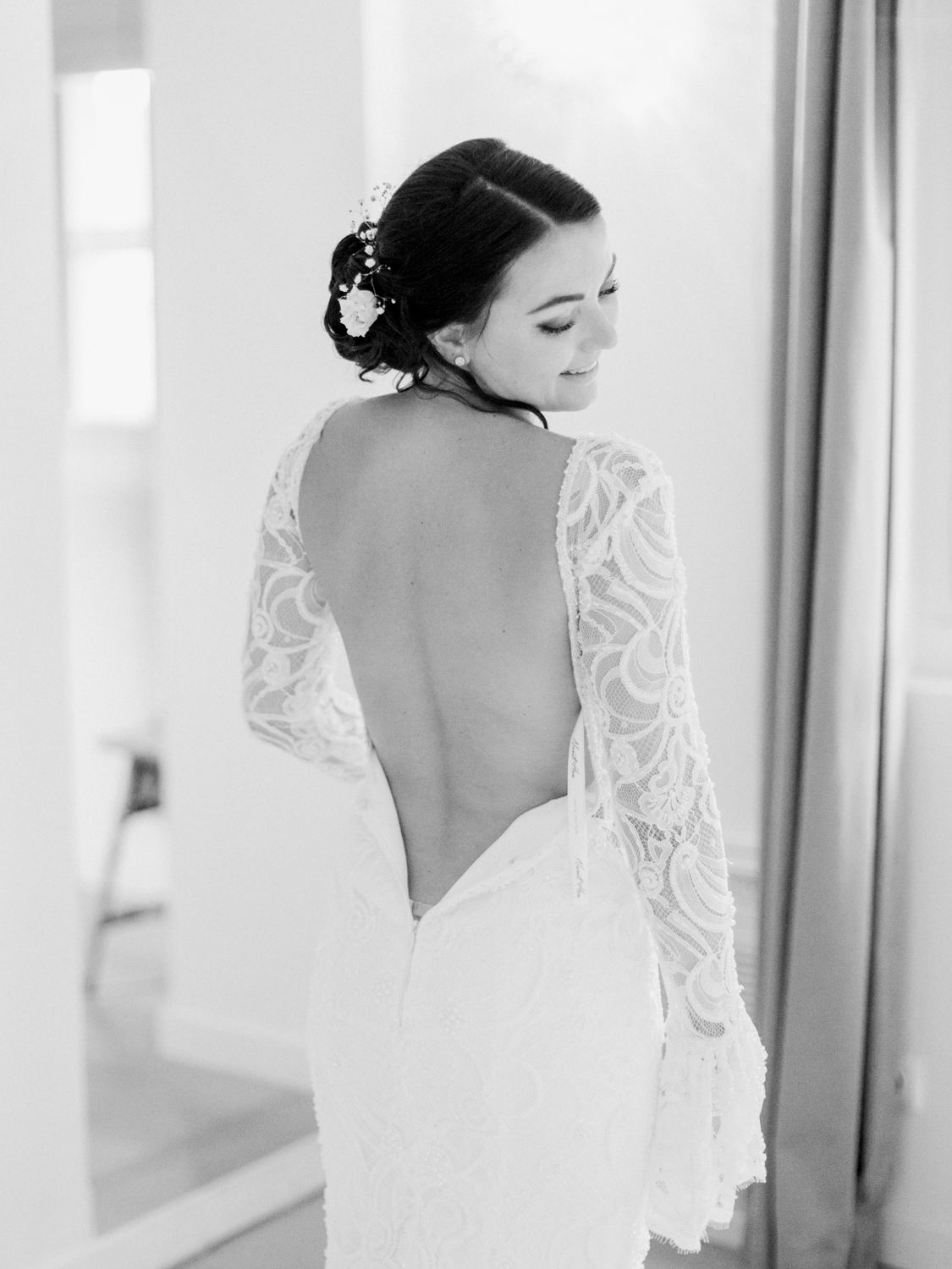 Mariée en robe de mariée élégante en dentelle dos nu à manches longues et accessoires floraux pour les cheveux, sur la Côte d'Azur