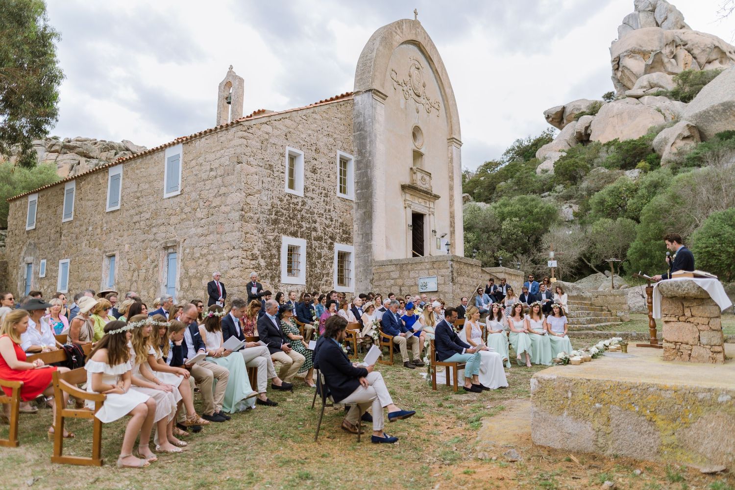 Cérémonie de mariage en plein air dans une chapelle rustique en pierre, entourée d'un paysage rocheux, à la trinité de Bonifacio.