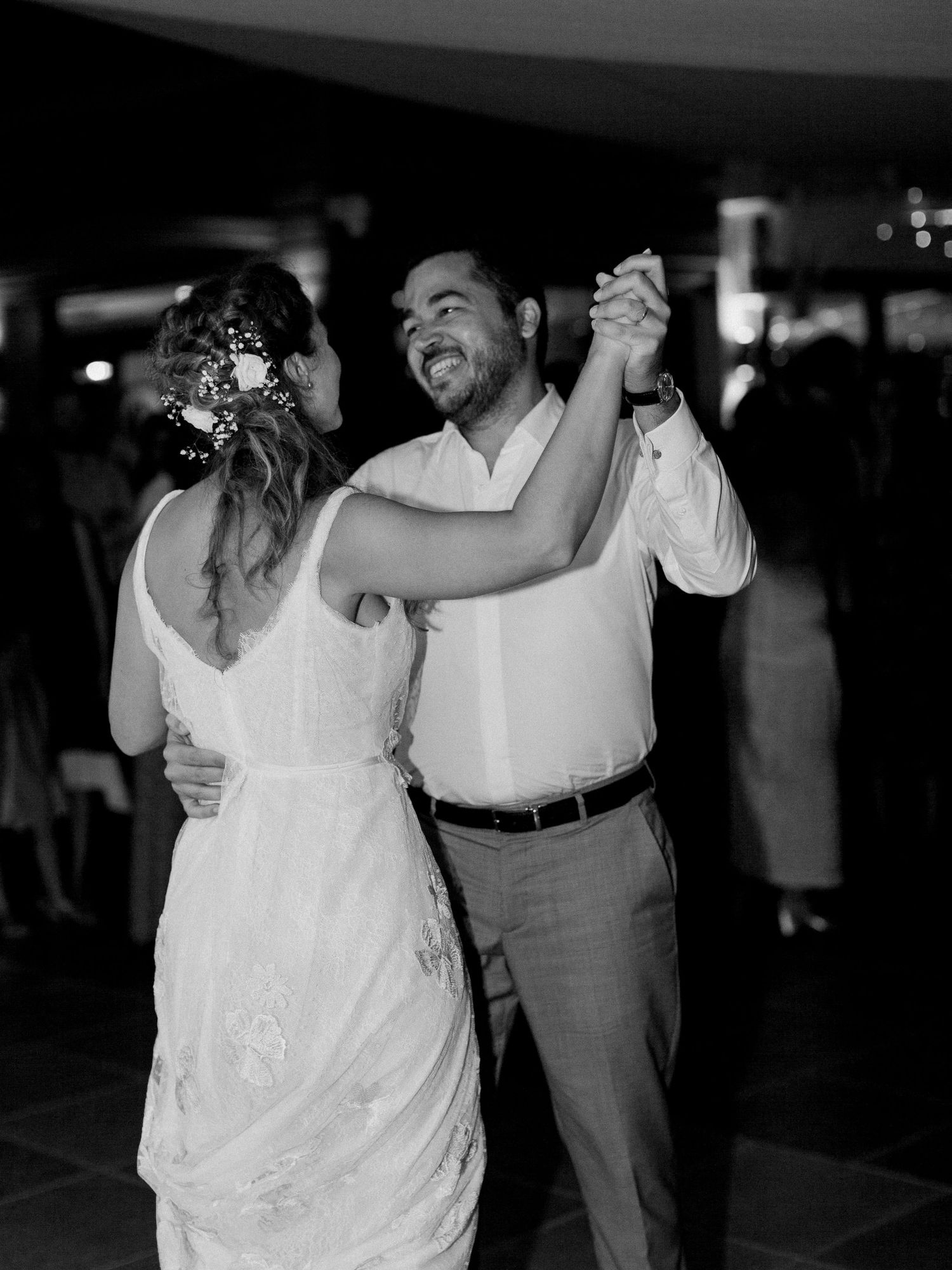 Photo en noir et blanc d'un marié souriant dansant avec sa mariée en robe de mariée lors de leur première danse.